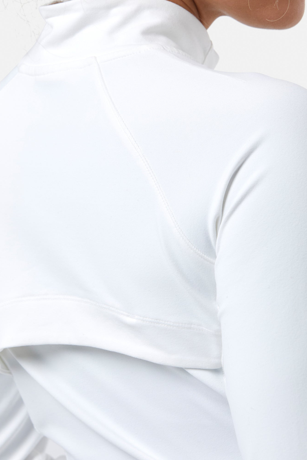 Minimalist close-up of white athletic jacket fabric showing detailed stitching of Gym+Coffee Relentless Full Zip Jacket in Ultra White, shop Gym+Coffee at Dotique
