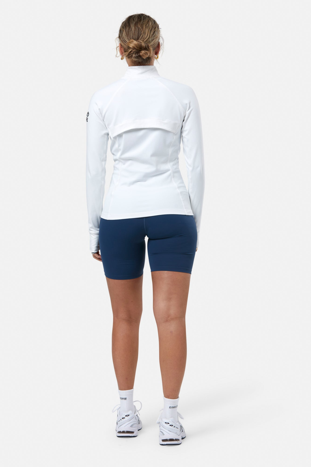 Rear view of a woman wearing Gym+Coffee Relentless Full Zip Jacket in Ultra White by Gym+Coffee, shop at Dotique.