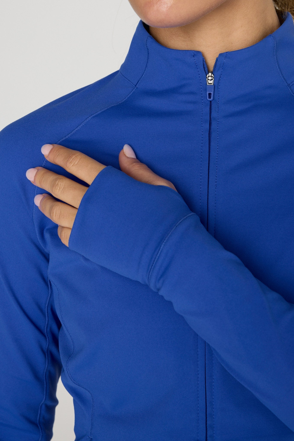 Close-up of a person wearing Gym+Coffee Relentless Full Zip Tidal Blue with thumb hole sleeves, shop Gym+Coffee at Dotique