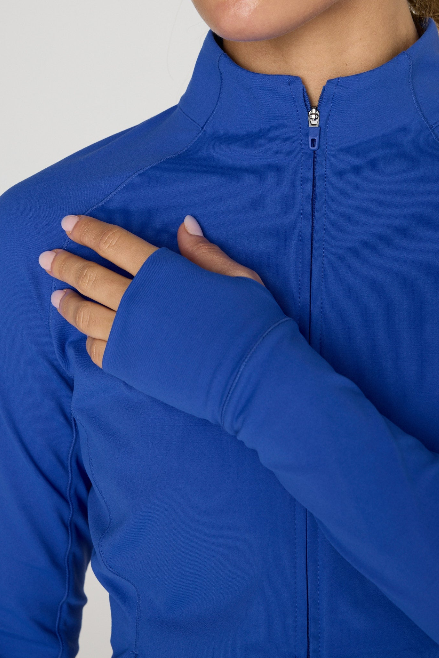 Close-up of a person wearing Gym+Coffee Relentless Full Zip Tidal Blue with thumb hole sleeves, shop Gym+Coffee at Dotique