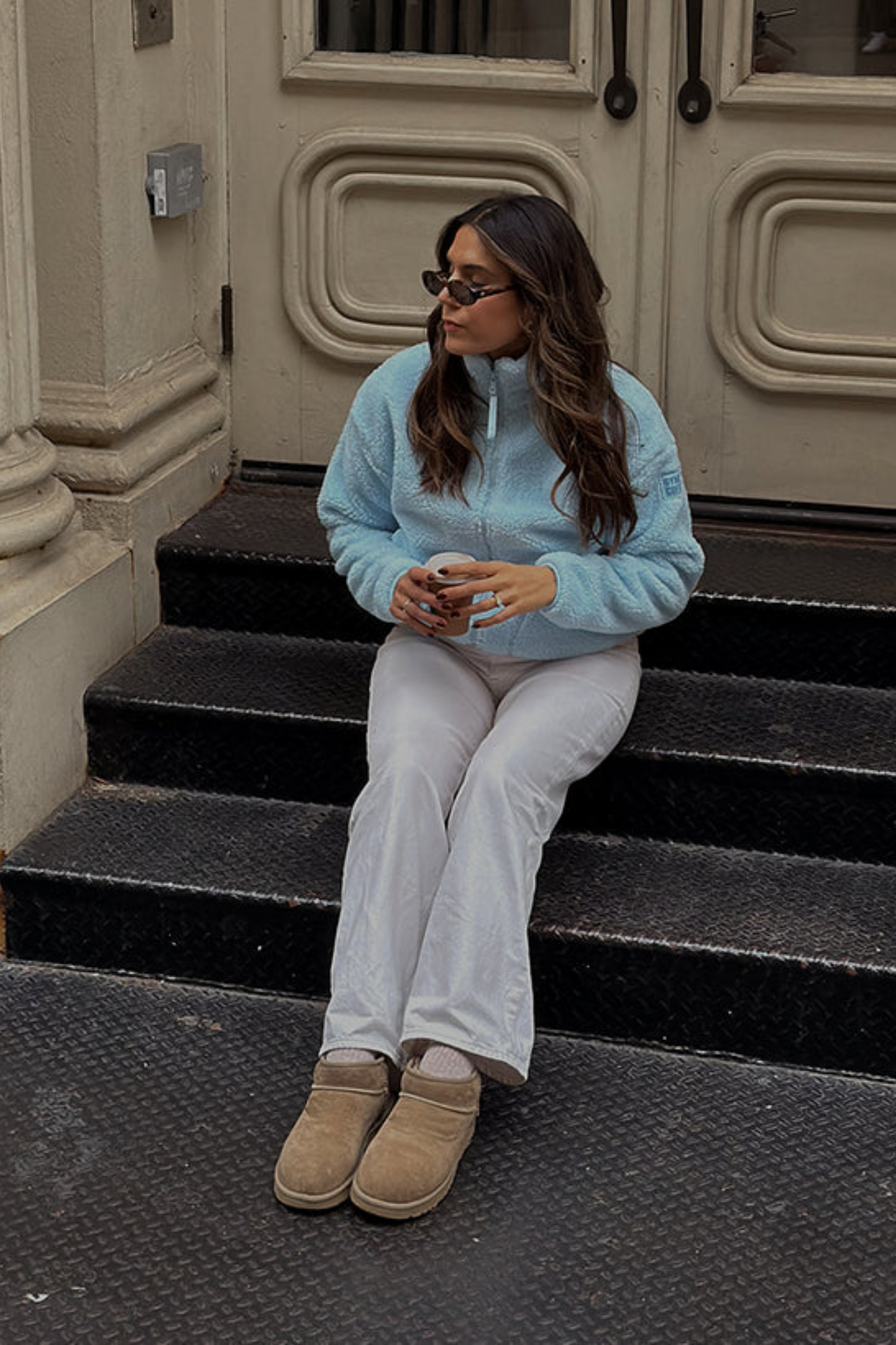 Woman sitting wearing Gym+Coffee Industry Fleece High Collar Jacket in Baby Blue by Gym+Coffee Shop Dotique stylish and cozy layer