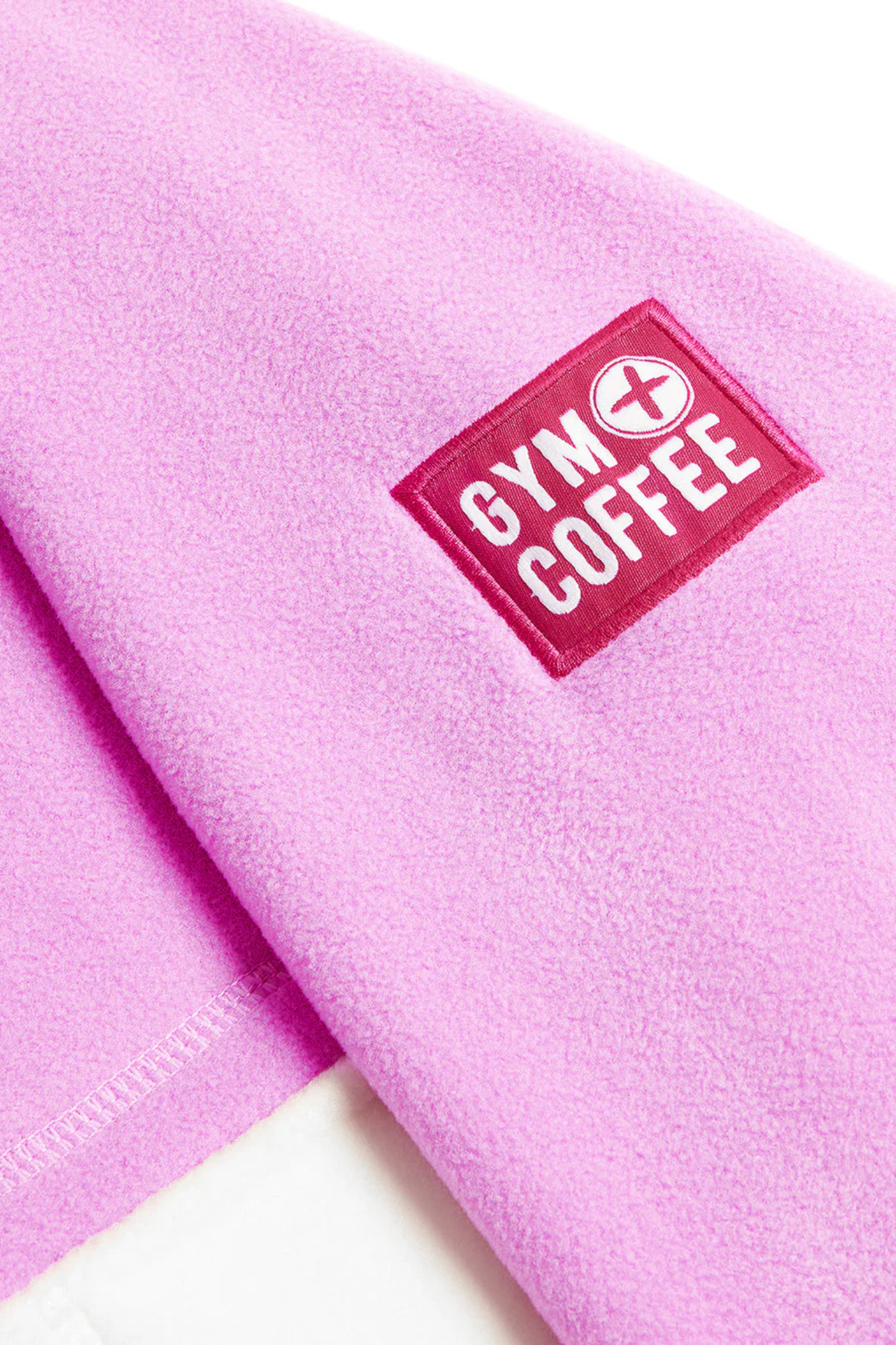Close-up of Gym+Coffee Snap Polar Fleece Neon Pink showing logo patch on soft fleece fabric Shop Gym+Coffee at Dotique