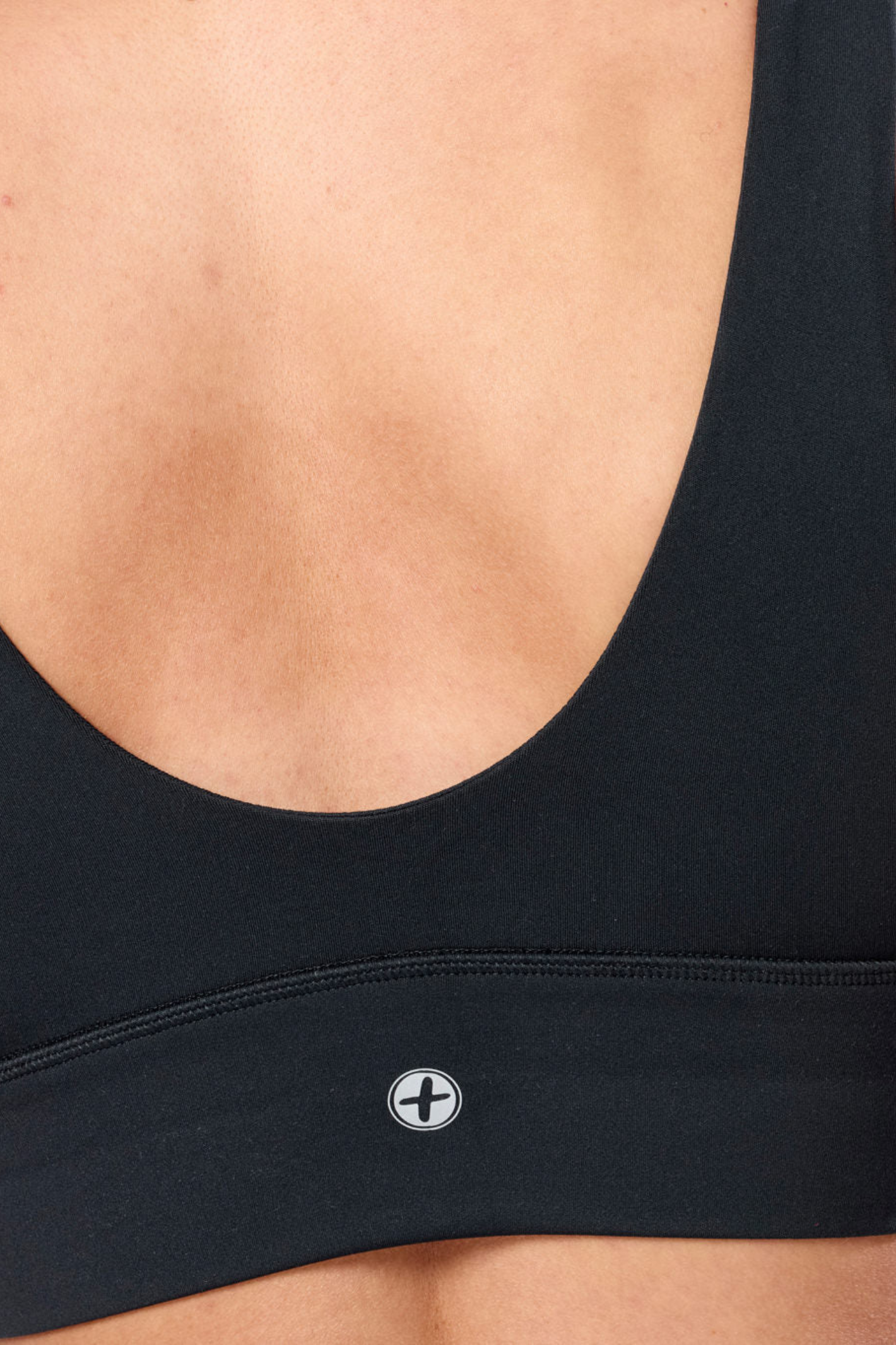 Close-up of Gym + Coffee Soft-Motion Bra Black showing fabric and logo, shop the Gym+Coffee brand at Dotique.