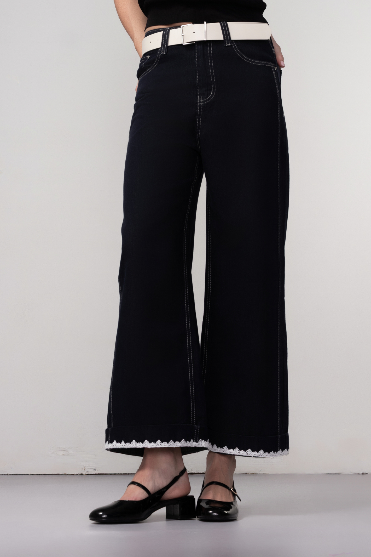 Haako dark blue wide leg jeans with contrast stitching and cream belt, styled for a modern minimalist look