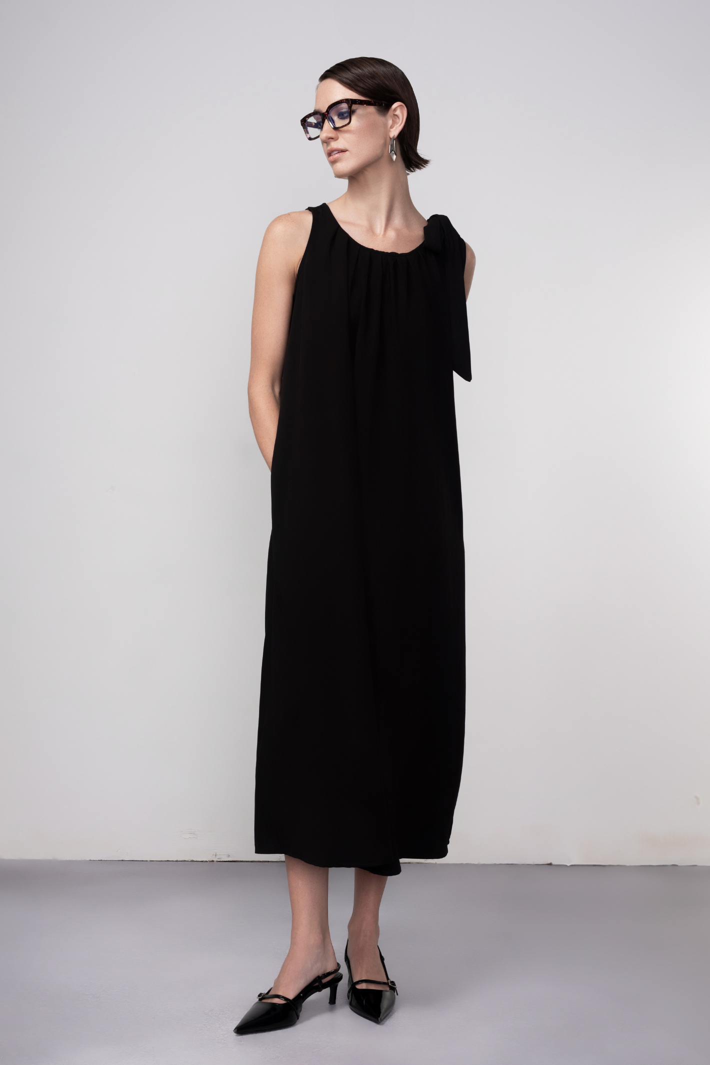 Haako black sleeveless midi dress with tie shoulder detail styled in a minimalist look at Dotique
