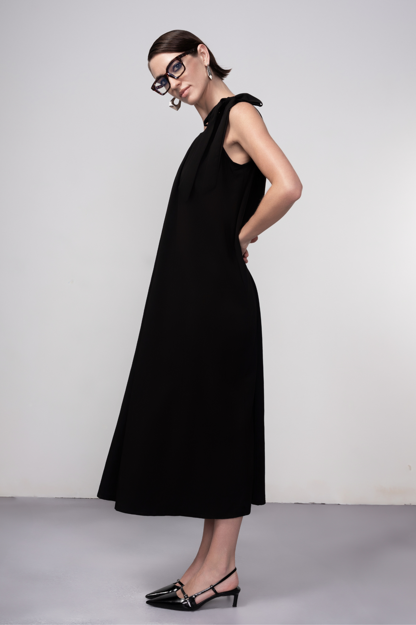 Haako black sleeveless midi dress with tie shoulder detail styled in a minimalist look at Dotique