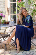 Woman wearing Hope & Ivy Sadie Flutter Sleeve Blue Maxi Dress with Tie Waist sitting outdoors Shop Hope and Ivy at Dotique