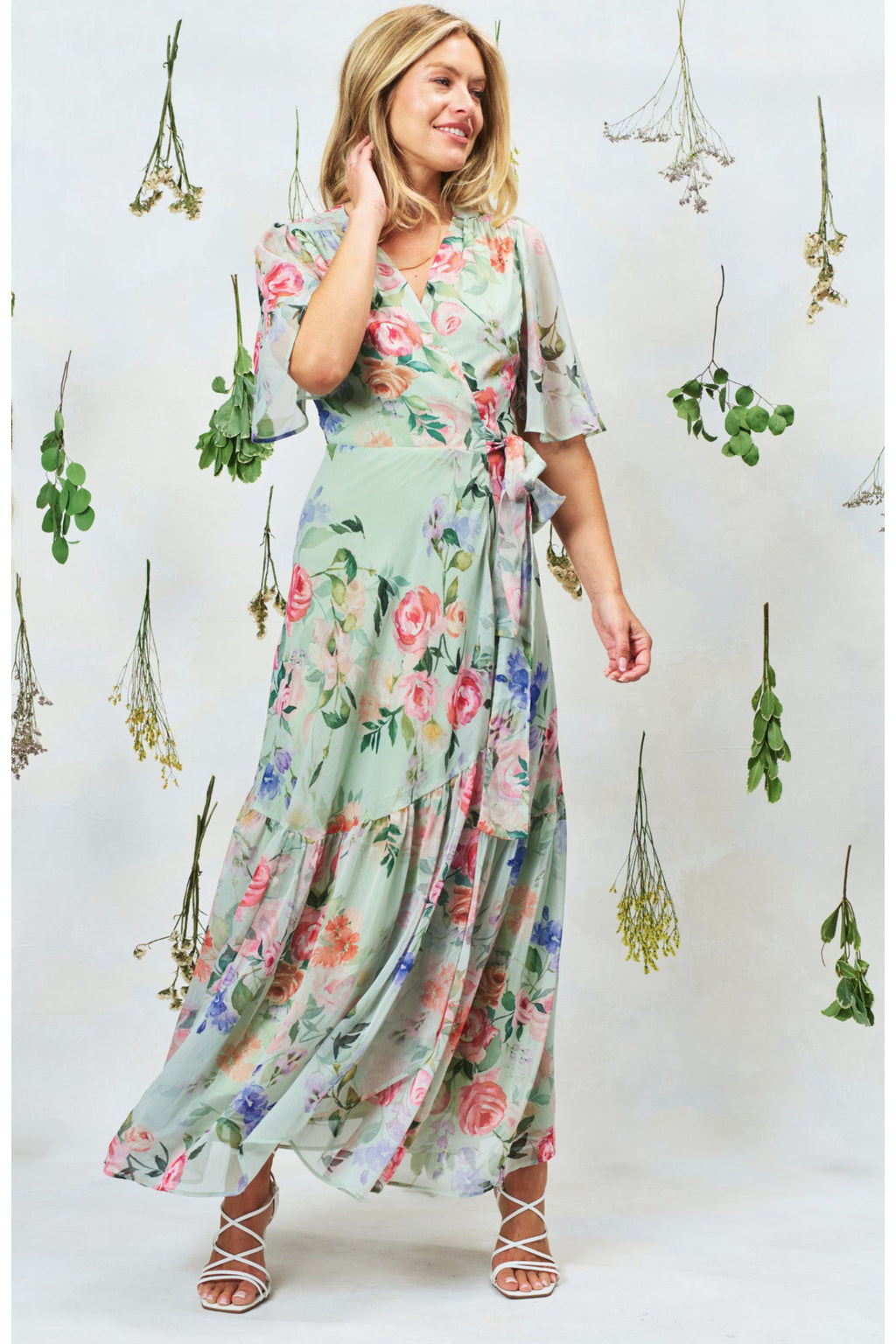 Hope & Ivy The Emi Flutter Sleeve Floral Wrap Maxi Dress Green by Hope and Ivy modeled with hanging greenery Shop Hope and Ivy at Dotique