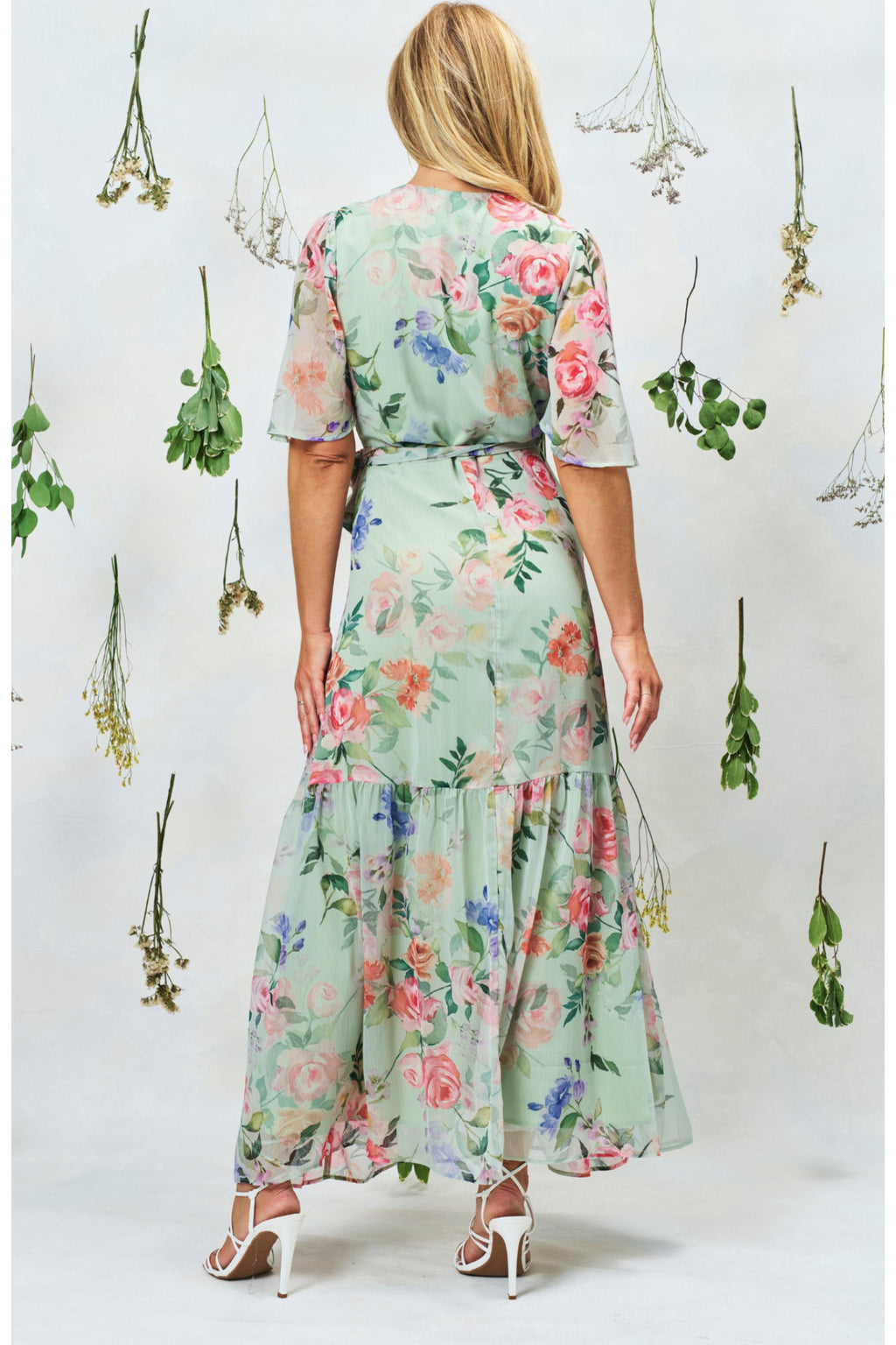 Woman wearing Hope & Ivy The Emi Flutter Sleeve Floral Wrap Maxi Dress Green by Hope and Ivy Shop the Vendor at Dotique