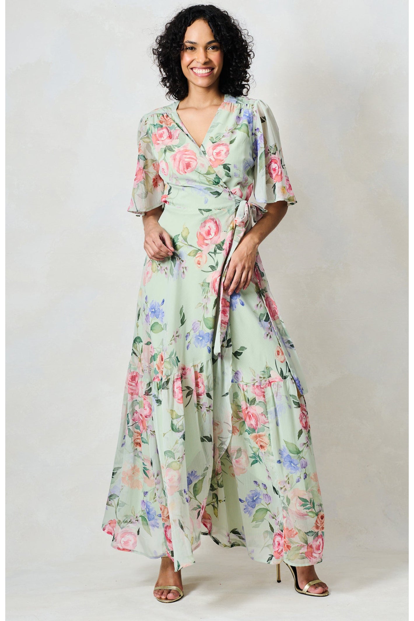 Woman wearing Hope & Ivy The Emi Flutter Sleeve Floral Wrap Maxi Dress Green by Hope and Ivy Shop Hope and Ivy at Dotique