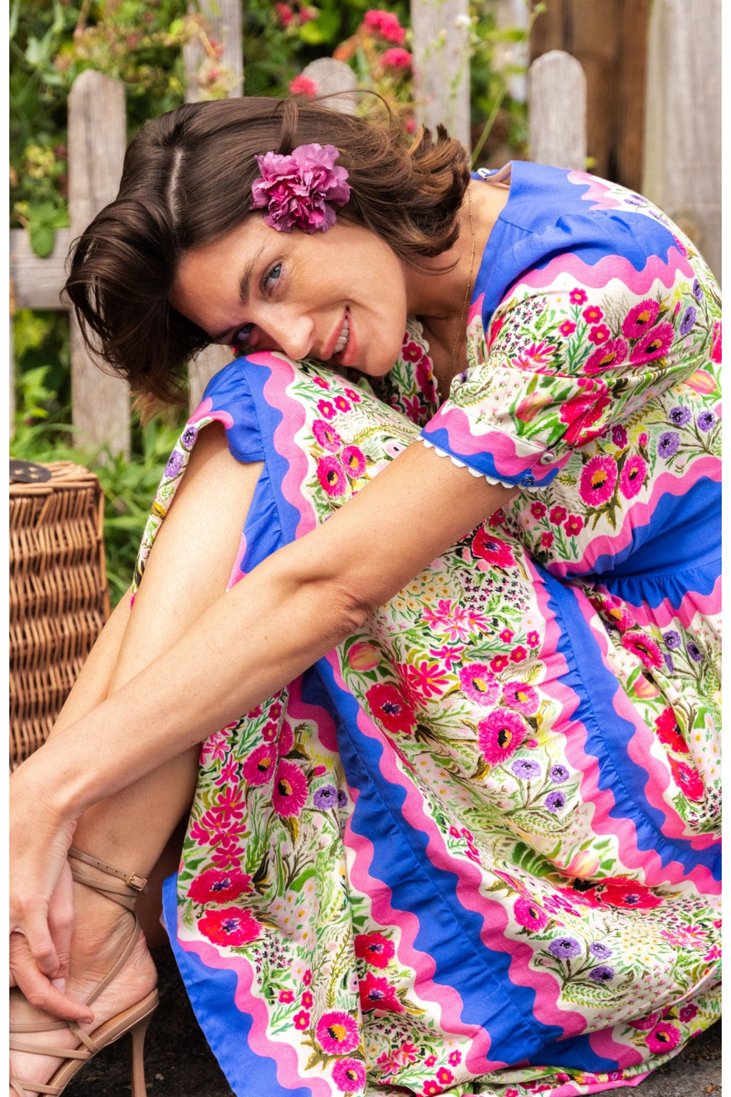 Woman wearing Hope & Ivy The Jo Blue & Pink Floral Tea Dress by Hope and Ivy sits outdoors, shop Dotique for Hope and Ivy.