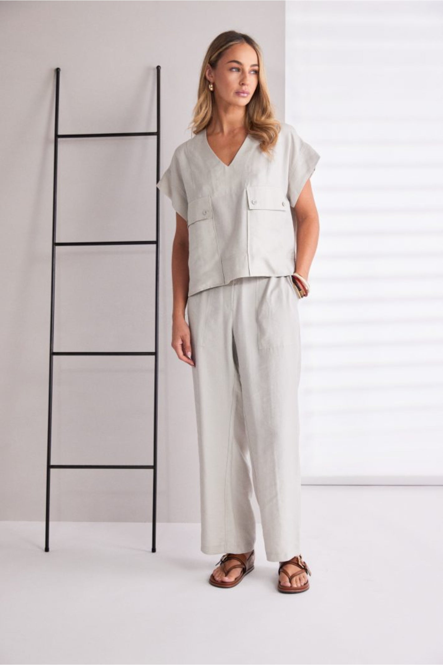 Model wearing Naya NPA26220 Patch Pocket Vee Neck Top With Button Detail Ash by Naya styled with relaxed trousers and sandals. Shop Naya at Dotique.