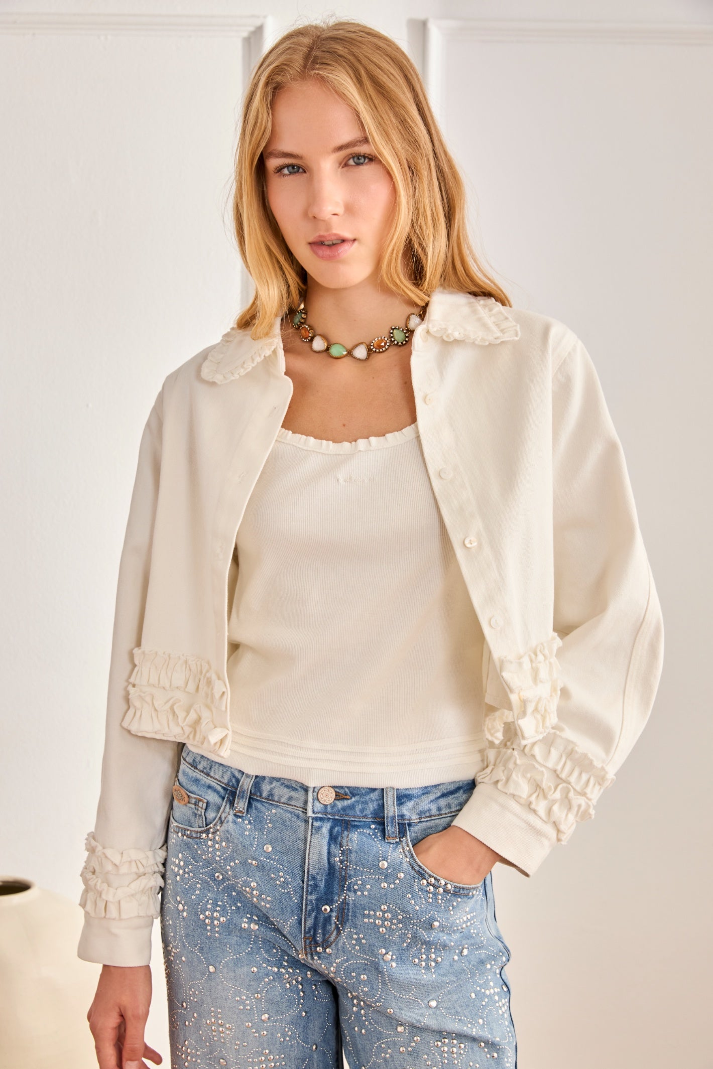 Blonde woman wearing NKN Nekane Kira White Cotton Jacket with Ruffles at the Hem by NKN Nekane shop at Dotique