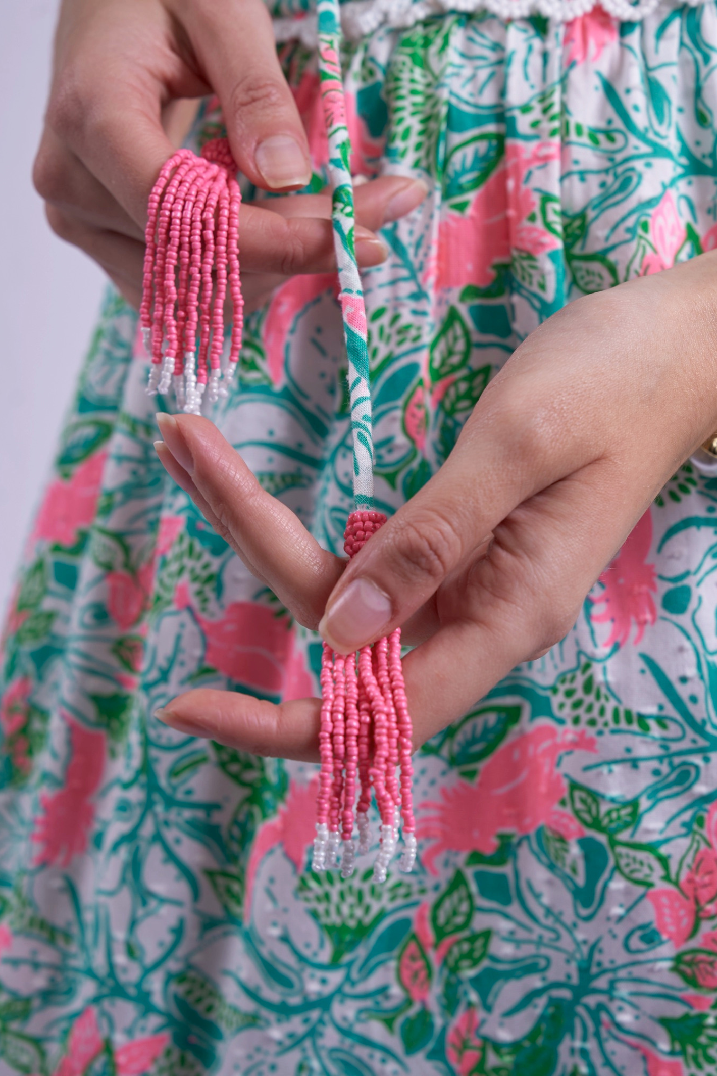 Close-up of decorative pink beaded tassel and floral fabric detail on New Day Originals Misha Pink Parrot by New Day Originals, shop New Day Originals at Dotique
