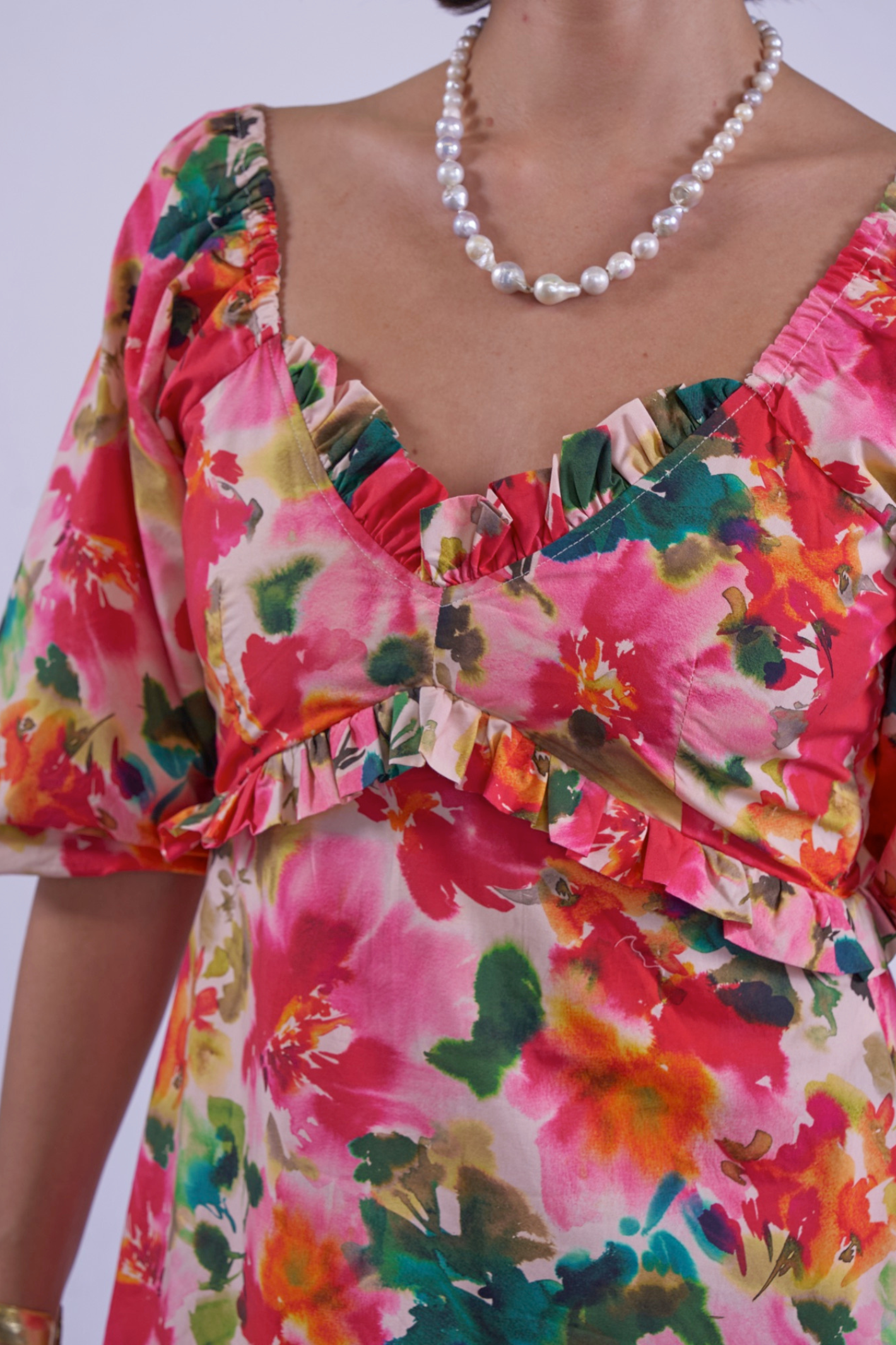 Close-up of vibrant floral print and ruffled neckline on New Day Originals Universe Dress Summer Bouquet by New Day Originals, shop Dotique