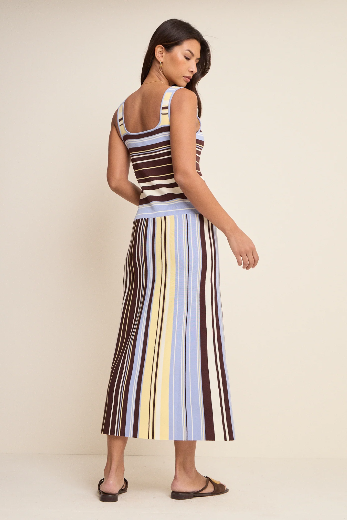 Model showcasing the back of Nobody’s Child Multi Stripe Knit Dress in soft blue, yellow, brown, and cream by Nobody’s Child, shop Nobody’s Child at Dotique.