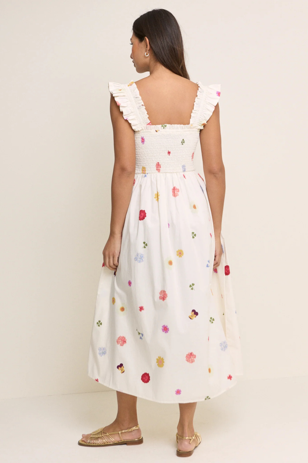 Model seen from back wearing Nobody’s Child Floral Shirred Christina Midi Dress in white cotton with colorful small floral prints and ruffled straps by Nobody’s Child. Shop Nobody’s Child at Dotique.