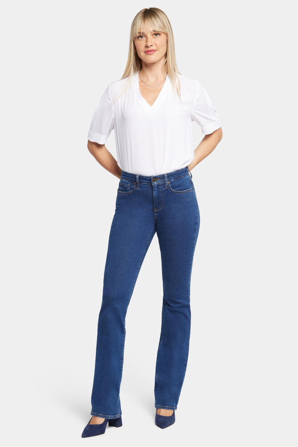 Woman wearing NYDJ Barbara Bootcut Quinn Jeans 30” in blue paired with white top, shop NYDJ at Dotique.