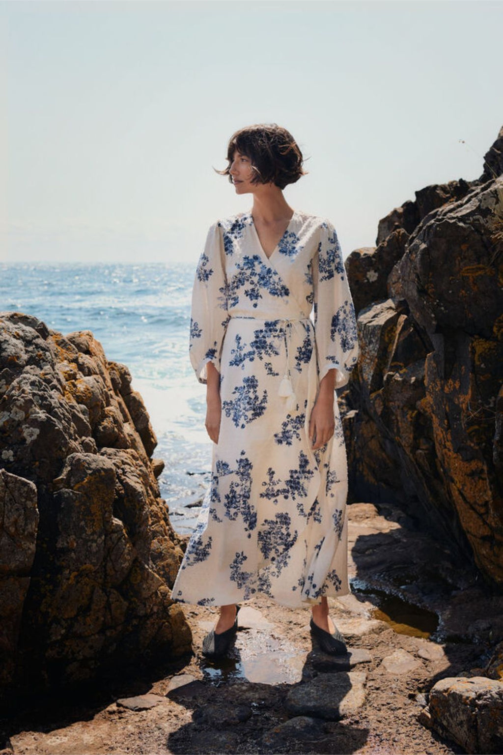 Woman standing by rocky shore wearing Part Two 30310448 AlyaPW Blue Shadow Flower Print Dress by Part Two Shop Part Two at Dotique