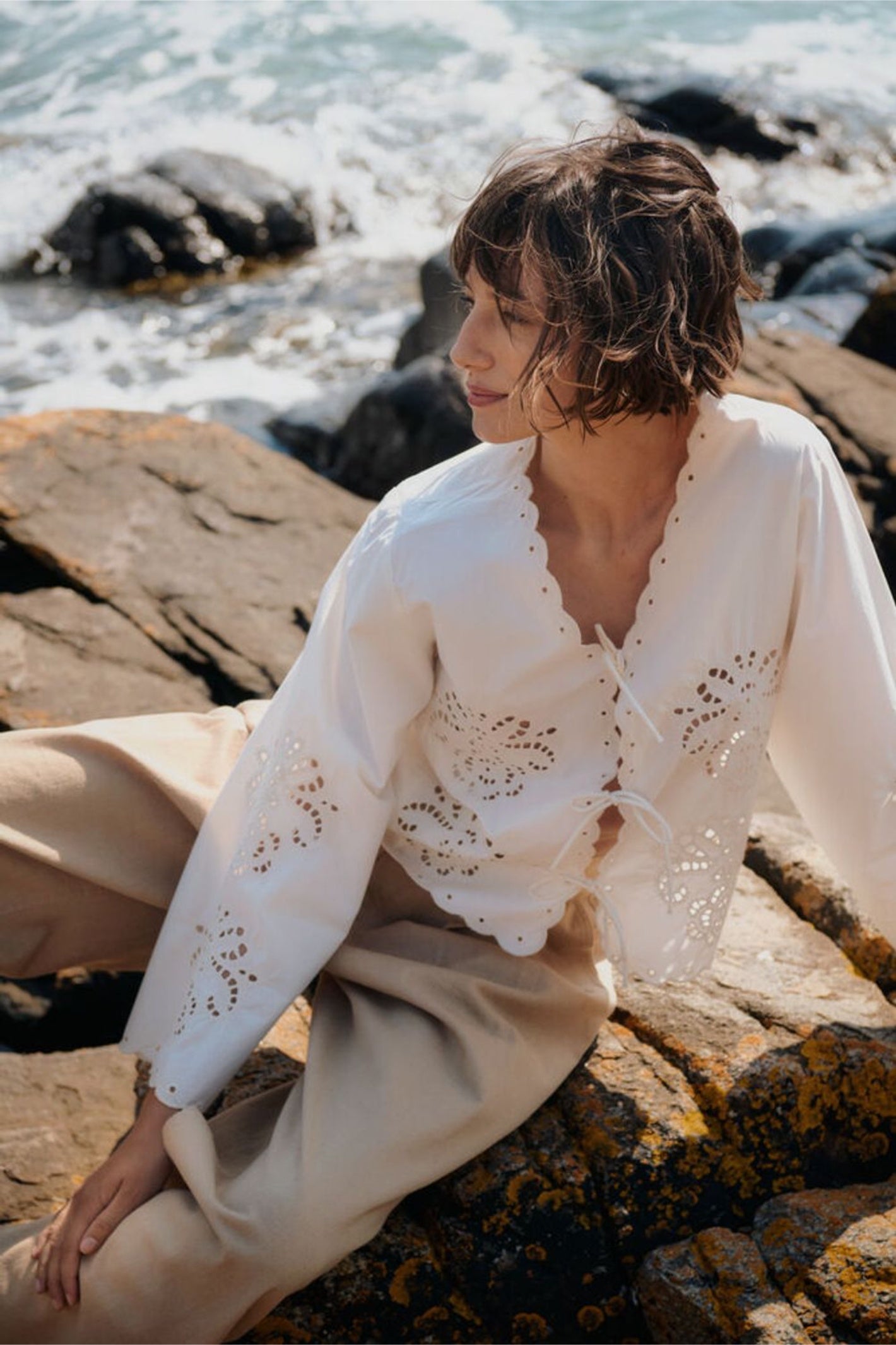 Woman wearing Part Two 30310454 AnamariaPW Whisper White Blouse by Part Two seated on rocks by water Shop Part Two at Dotique