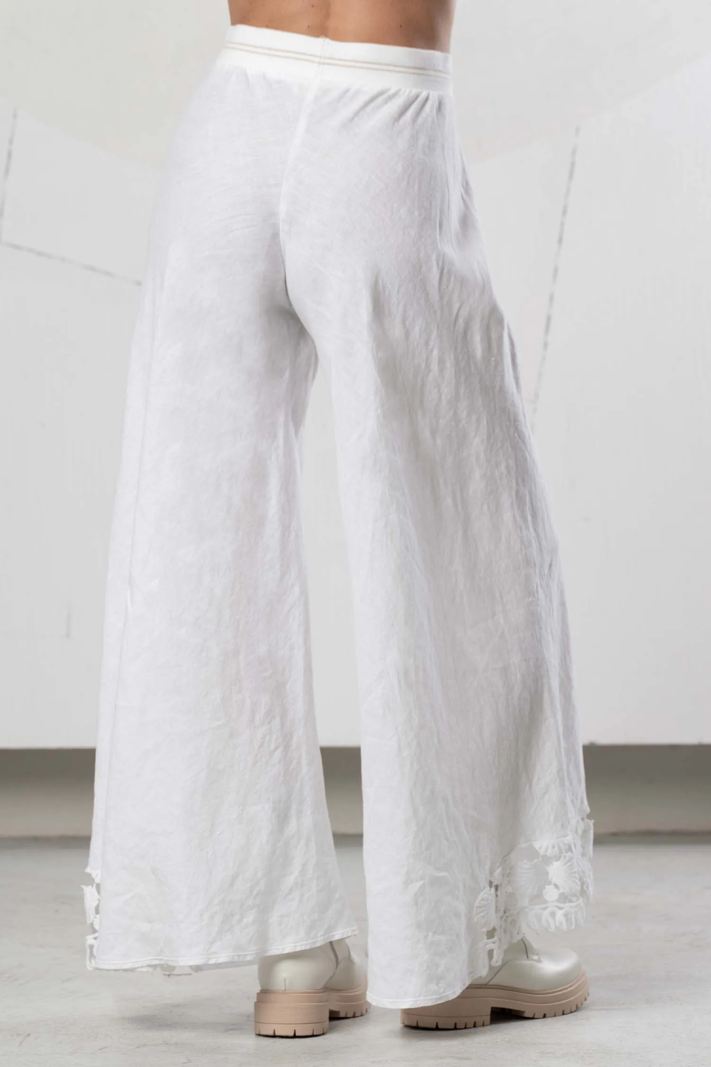 Rear view of model wearing Elisa Cavaletti Bianco Linen Wide Leg Trousers EAP266098201 01001 in white linen with embroidered hem, shop Elisa Cavaletti at Dotique.