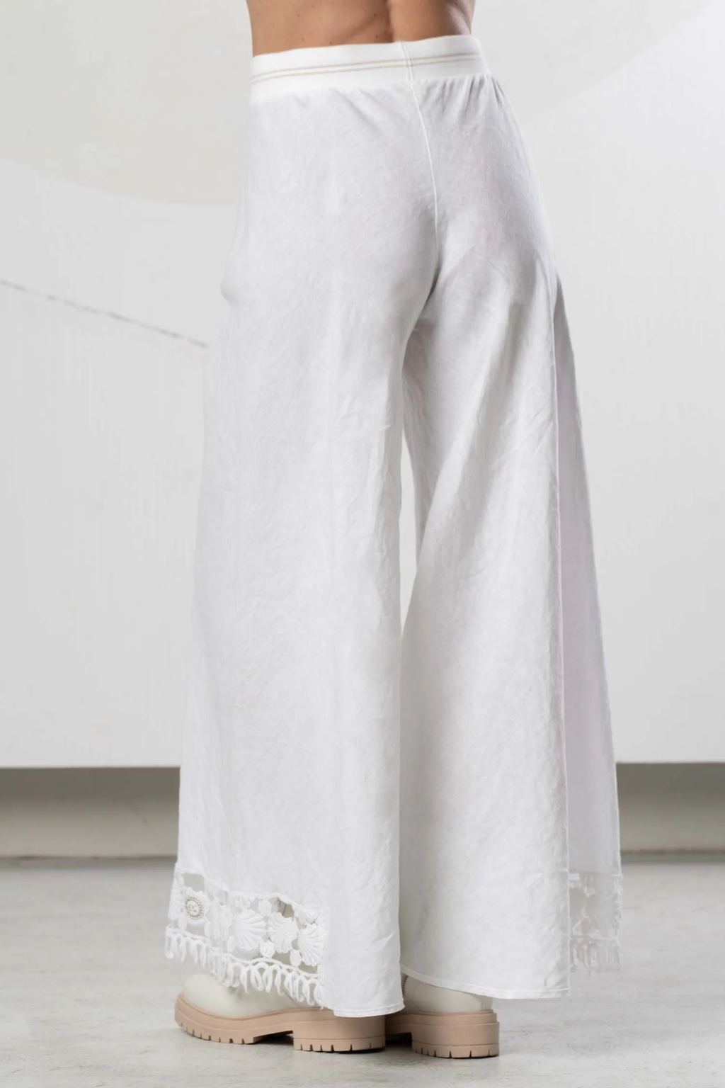 Rear view of model wearing Elisa Cavaletti Bianco Linen Wide Leg Trousers EAP266098201 01001 in white linen with floral lace hem detail by Elisa Cavaletti, shop Elisa Cavaletti at Dotique.