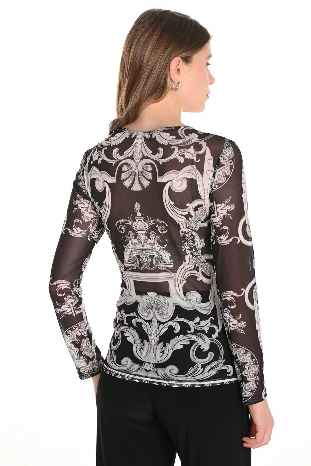 Woman wearing a black long-sleeve top with intricate white patterns on a white background