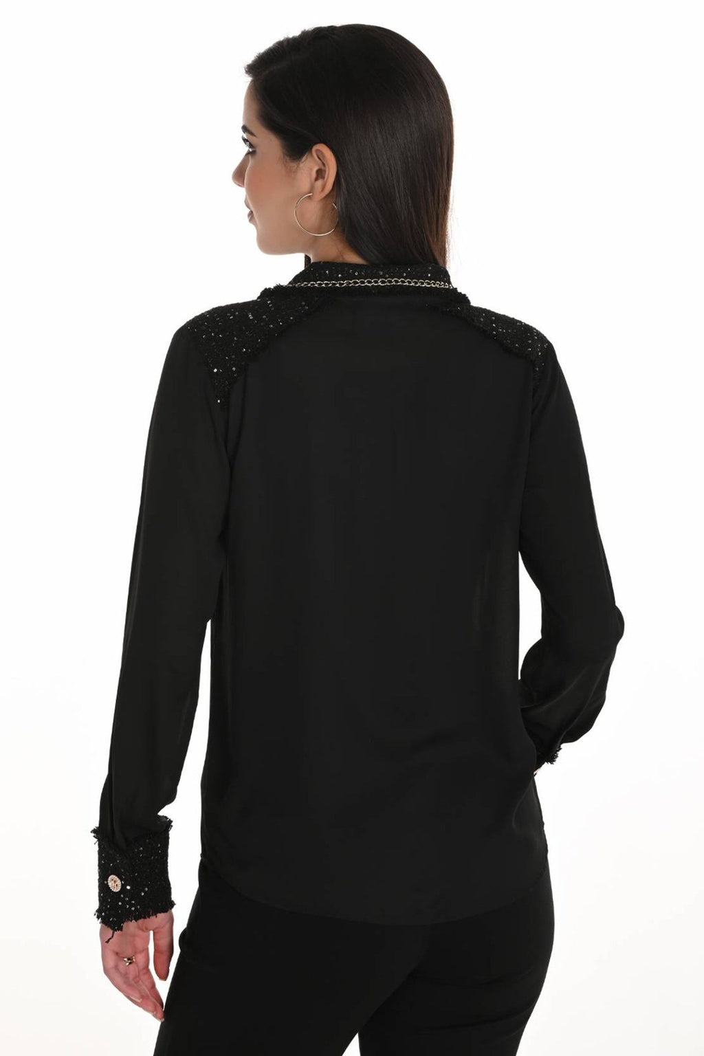 Black long-sleeve top with embellishments on a white background