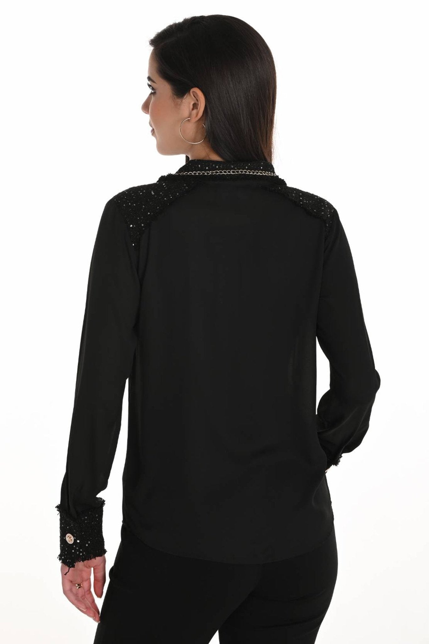 Black long-sleeve top with embellishments on a white background