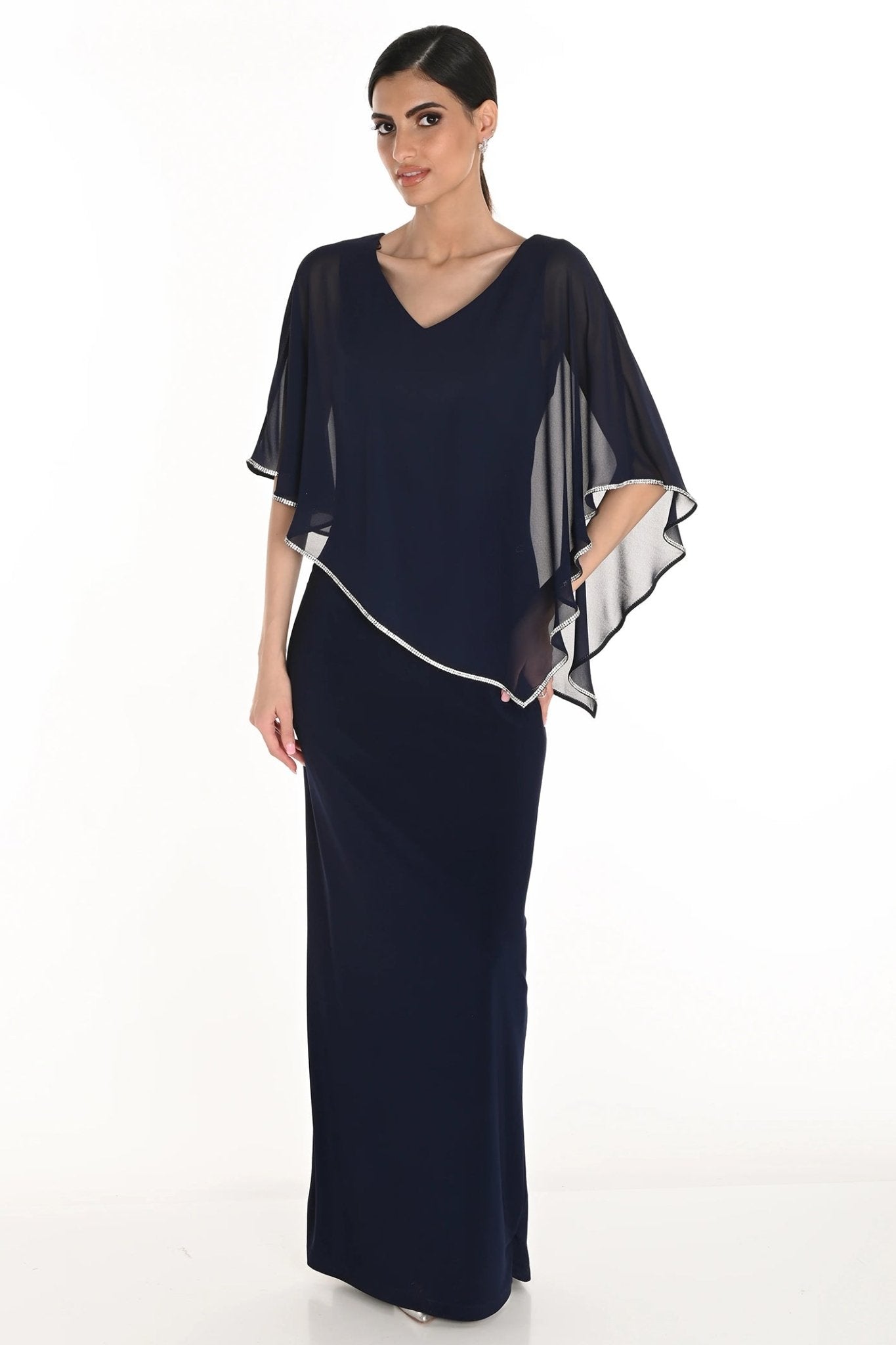 Woman wearing a navy blue evening gown with a sheer white overlay on a white background