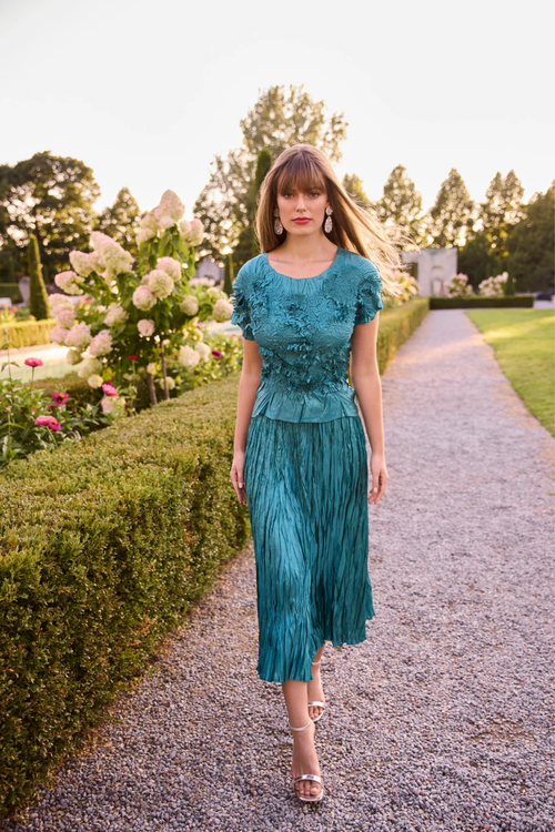 Model walking in a textured teal green top and pleated skirt from Frank Lyman 268521 Green Top and Skirt by Frank Lyman, shop Frank Lyman at Dotique.