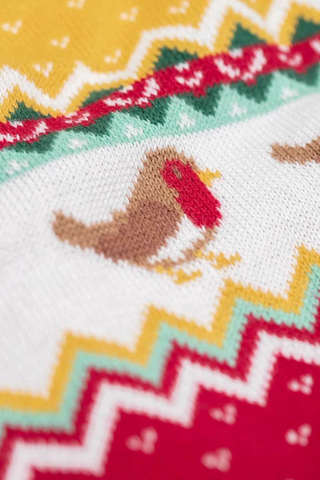 Close-up of a knitted fabric with a robin design and zigzag pattern.