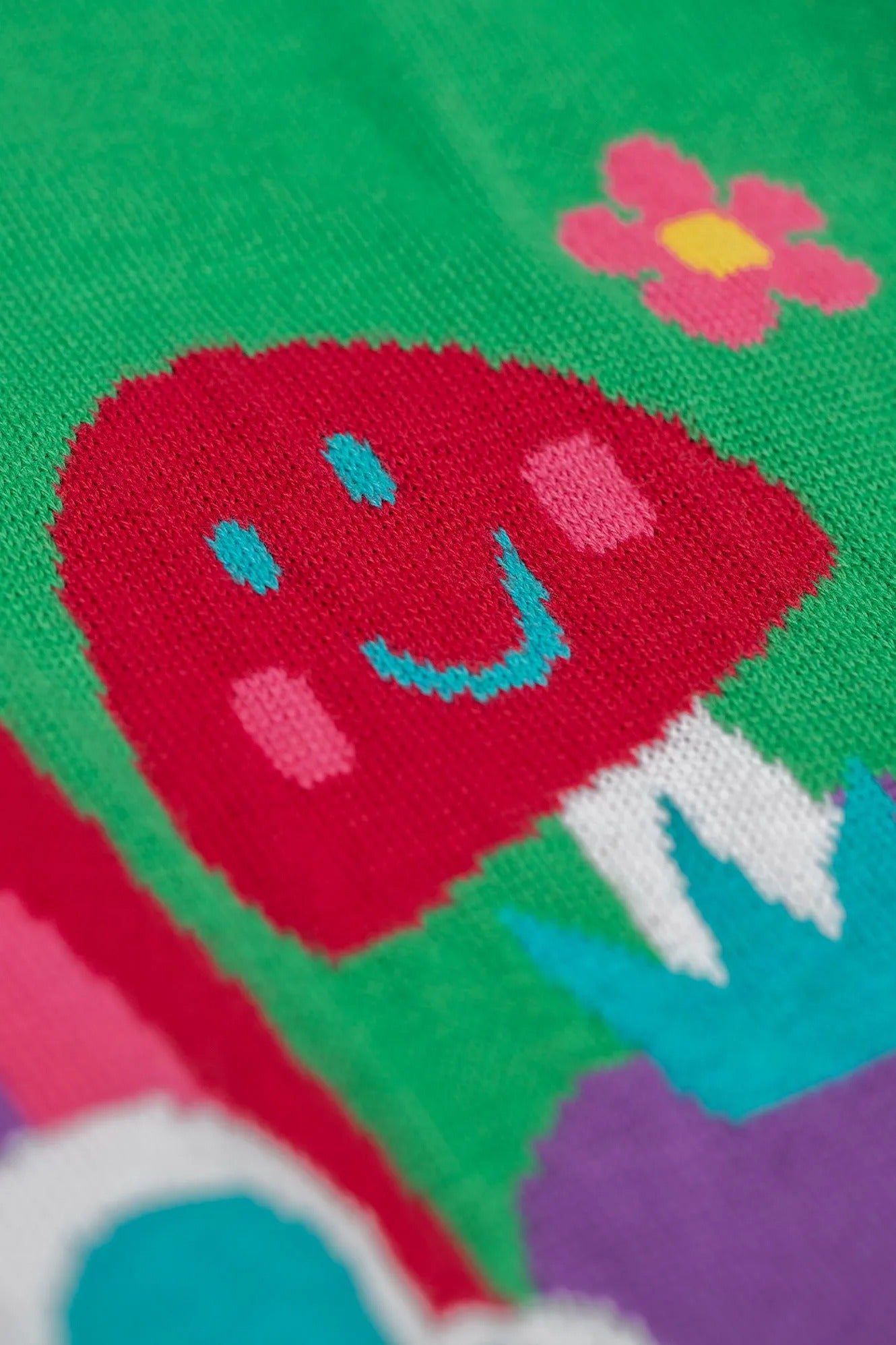 Colorful fabric with a red character and pink flower on a green background