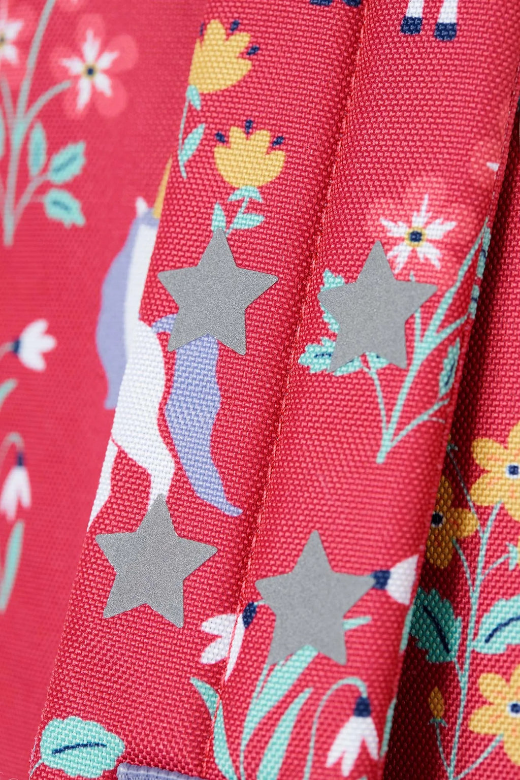 Close-up of a fabric with stars, flowers, and animals on a red background