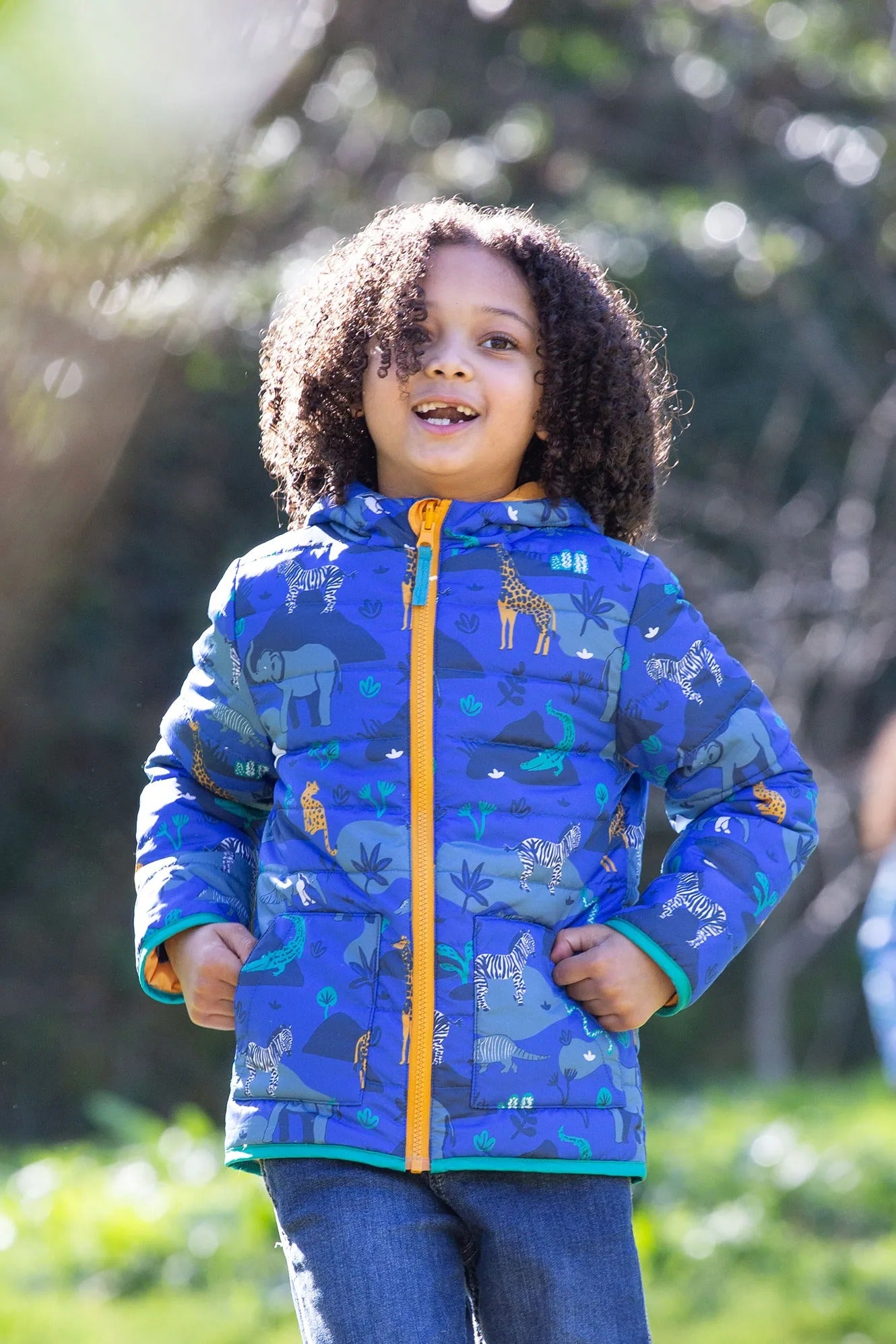 Child wearing a blue jacket with animal prints outdoors