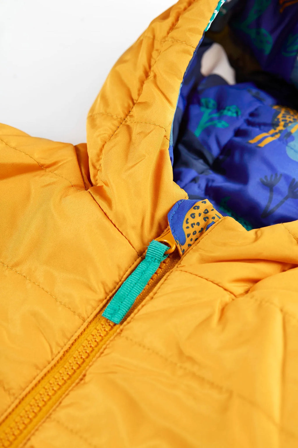 Close-up of a yellow puffer jacket with a blue interior lining on a white background