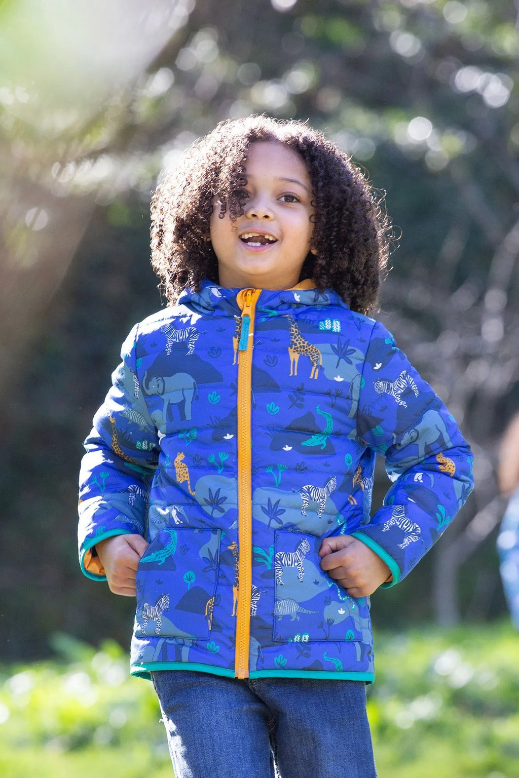 Child wearing a blue jacket with animal prints outdoors