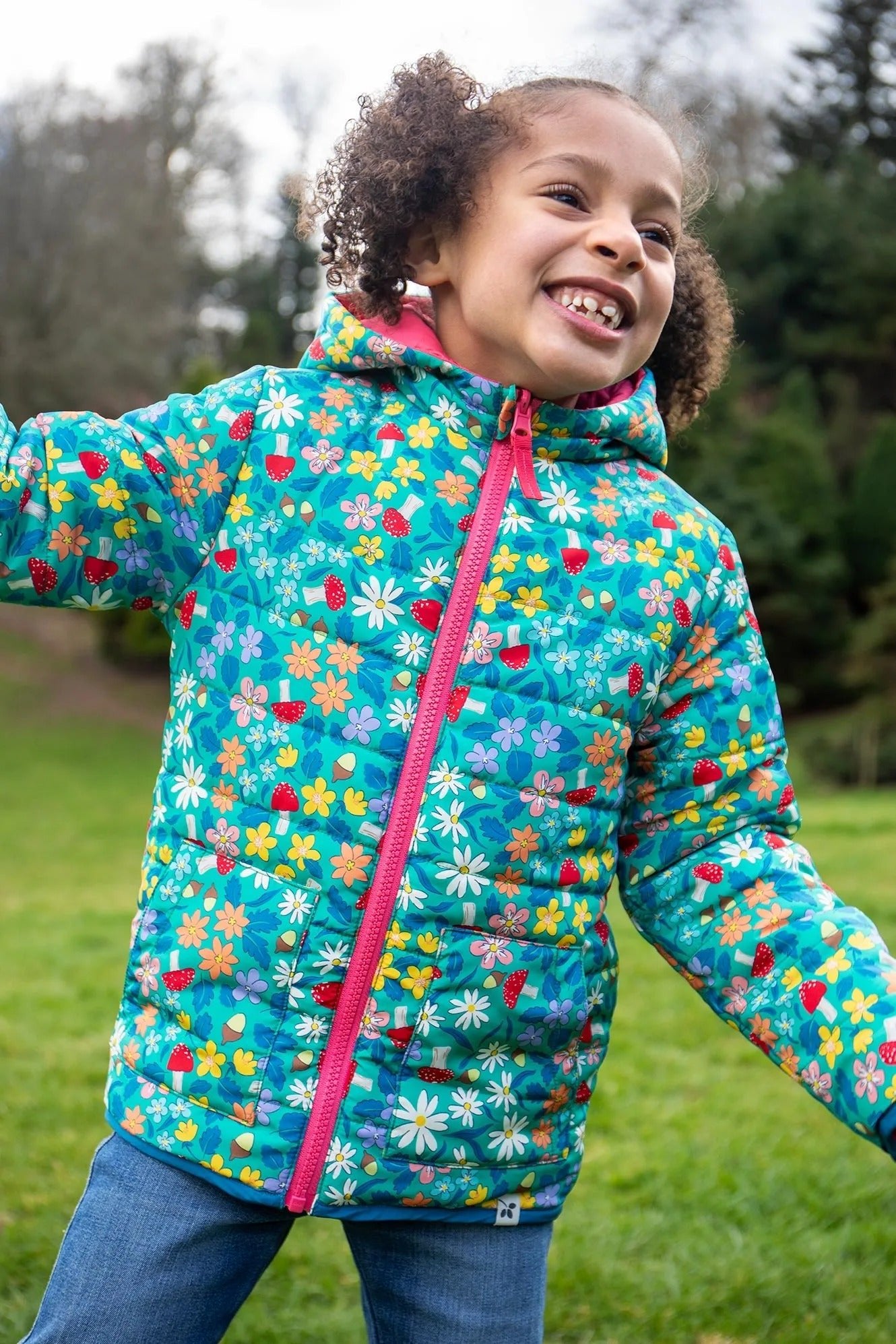 Child wearing a colorful floral jacket outdoors on a grassy area