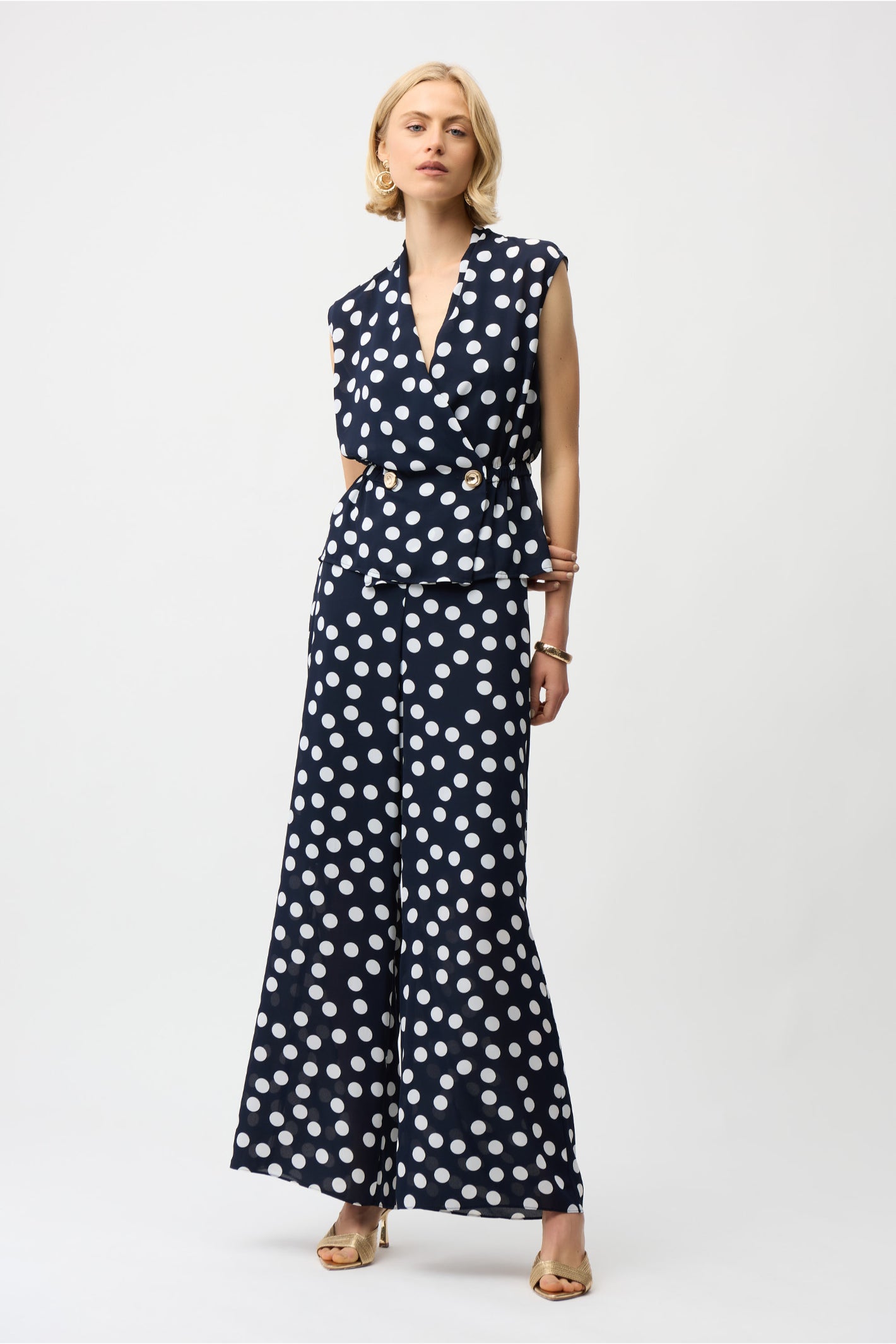 Model wearing Joseph Ribkoff 261250 Georgette Dot Print Wrap Peplum Top With Gold Buttons in navy with white dots by Joseph Ribkoff, shop Joseph Ribkoff at Dotique.
