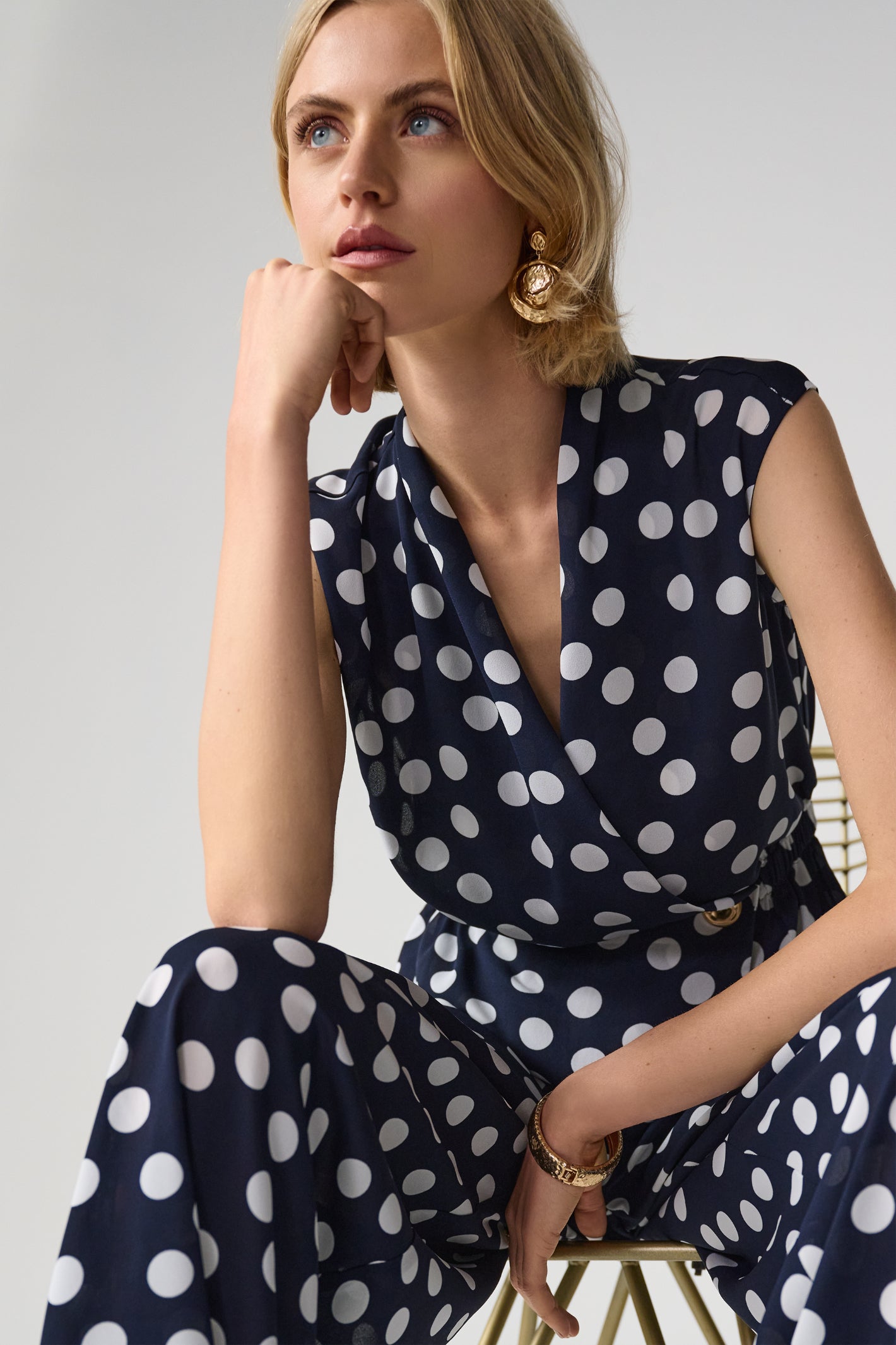 Model wearing Joseph Ribkoff 261250 Georgette Dot Print Wrap Peplum Top With Gold Buttons in navy with white polka dots by Joseph Ribkoff, shop Joseph Ribkoff at Dotique.