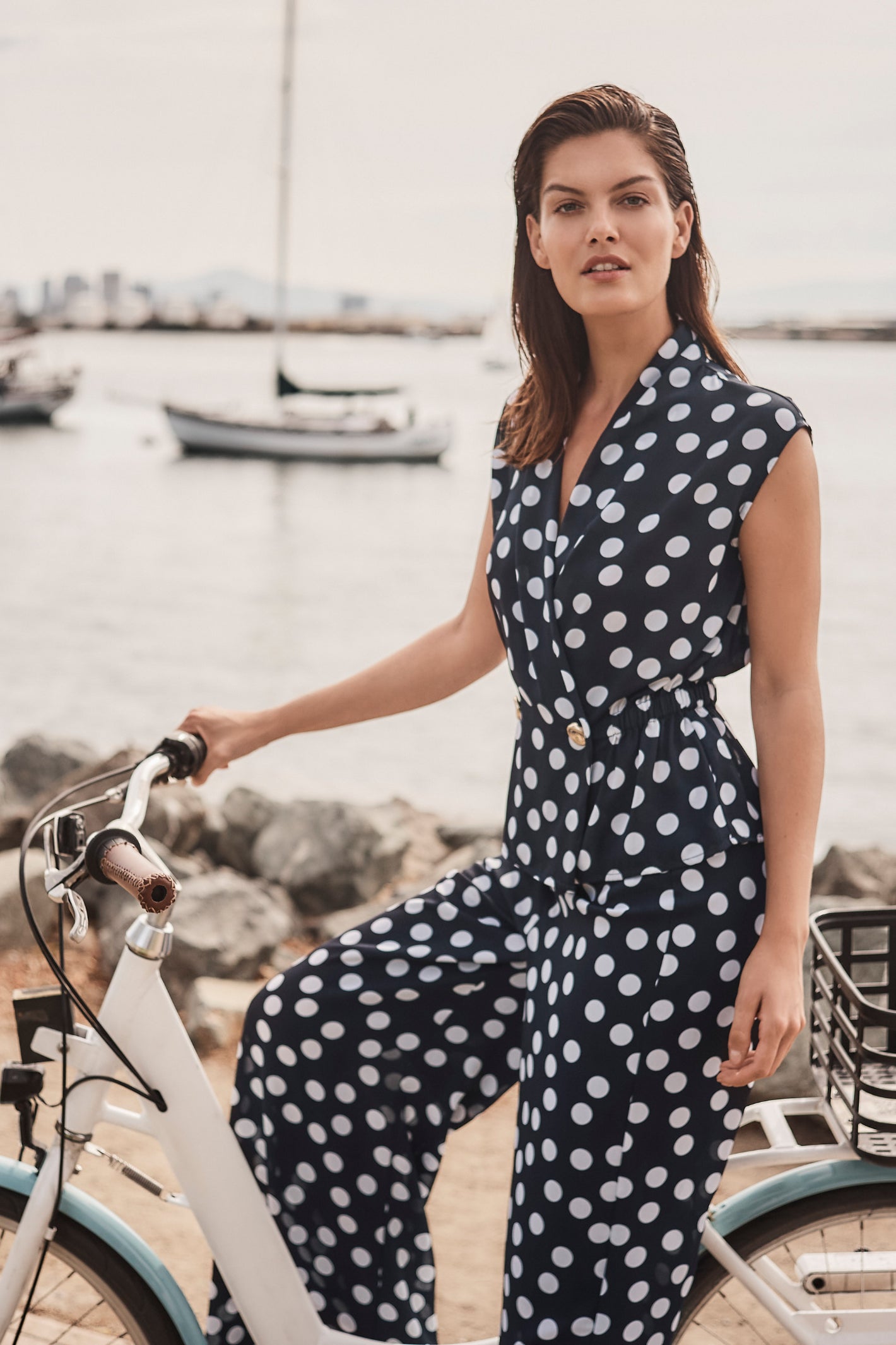 Model wearing Joseph Ribkoff 261250 Georgette Dot Print Wrap Peplum Top With Gold Buttons in navy with white dots by Joseph Ribkoff, shop Joseph Ribkoff at Dotique.