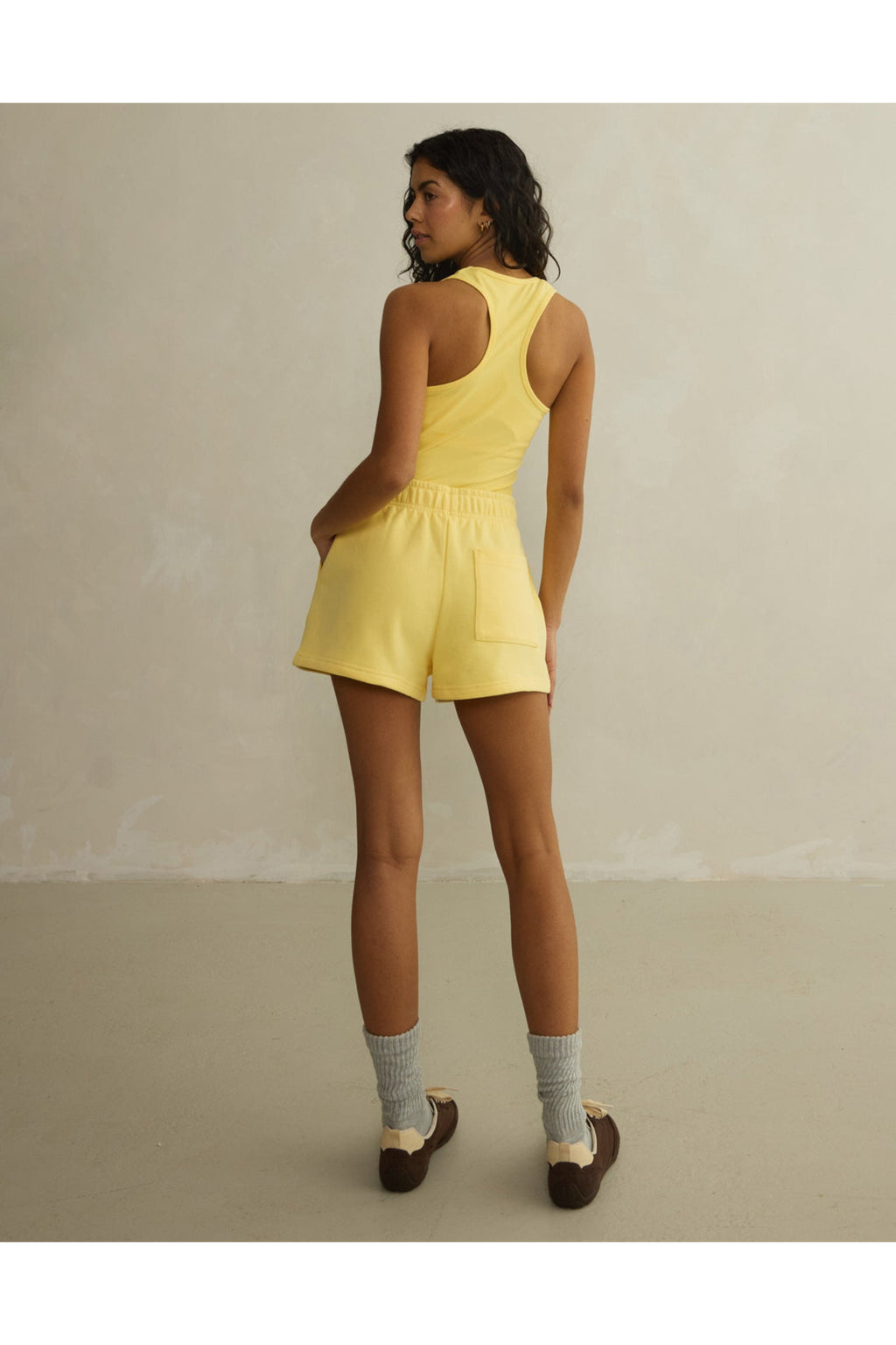 Rear view of model in Gym+Coffee Daily Cotton Shorts in Lemon Sorbet with elastic waist, shop Gym+Coffee at Dotique