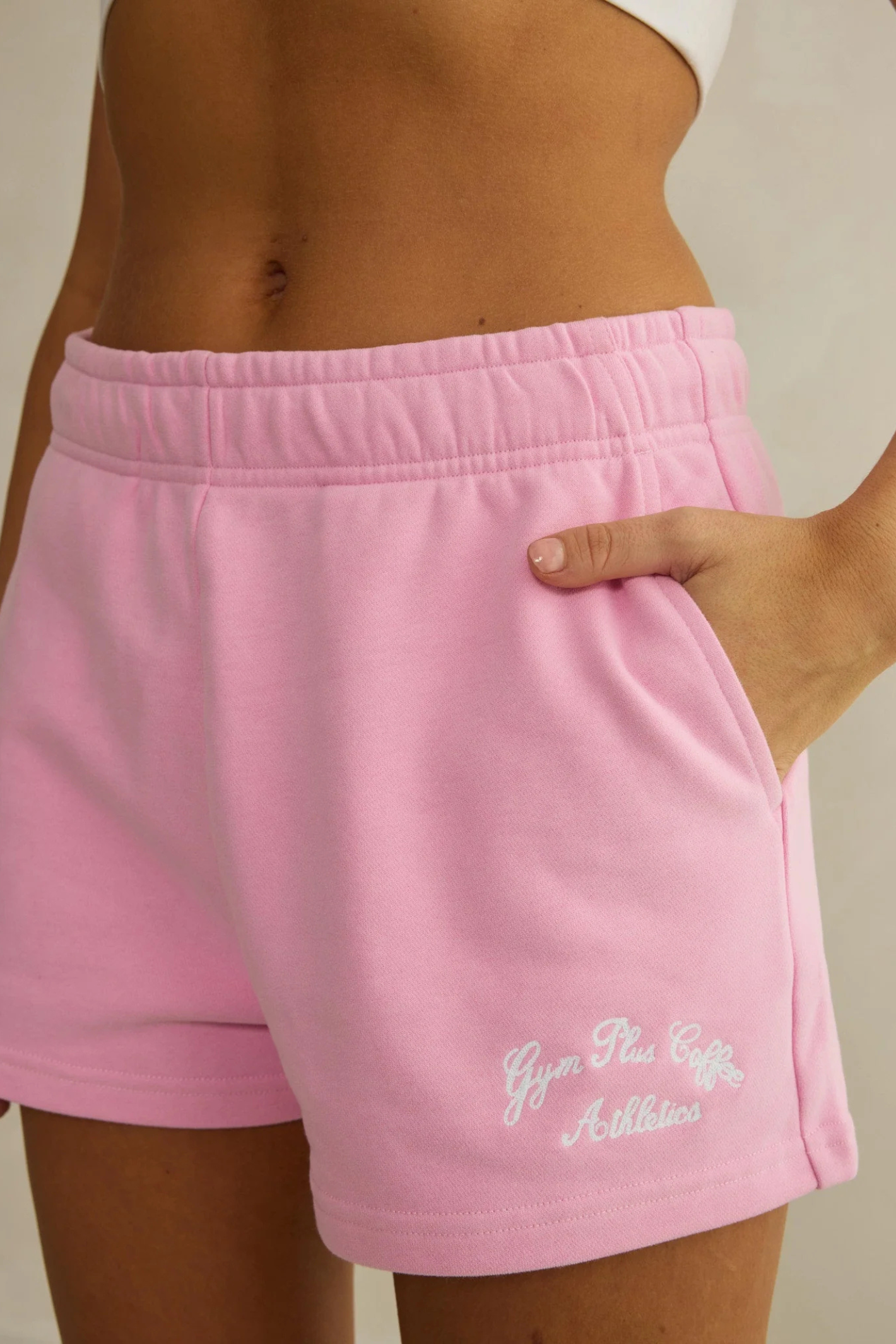 Close-up of Gym+Coffee Daily Cotton Shorts in Pink Blossom by gym+coffee showing embroidered logo and side pocket, shop gym+coffee at Dotique