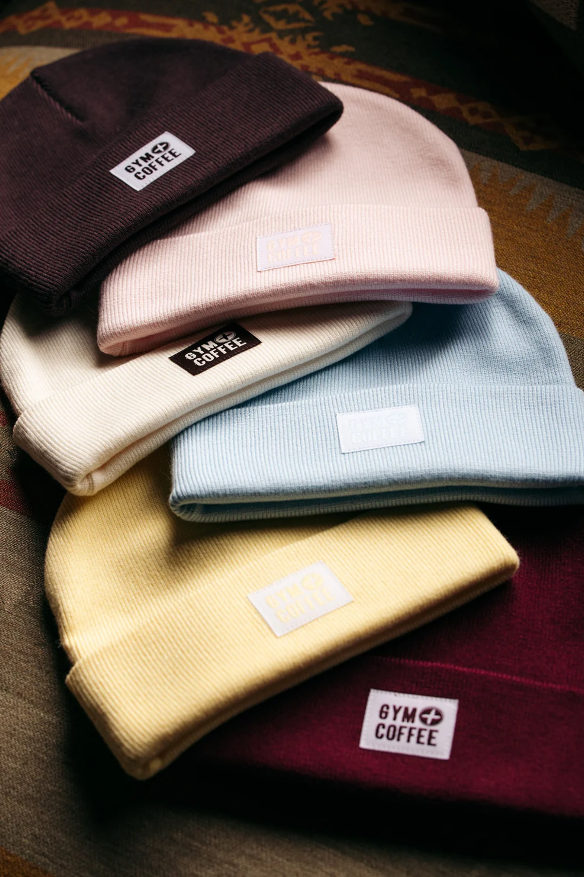 Gym+Coffee Knit Beanie Glacial Blue shown in a stack of knit beanies. Shop Gym+Coffee at Dotique.