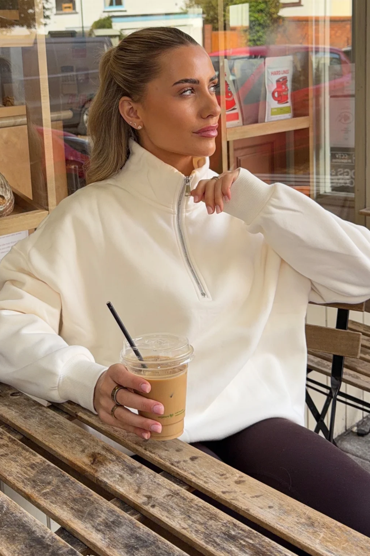 Gym+Coffee Sierra Half Zip Sweatshirt Ecru worn by woman in cafe. Shop Gym+Coffee at Dotique.