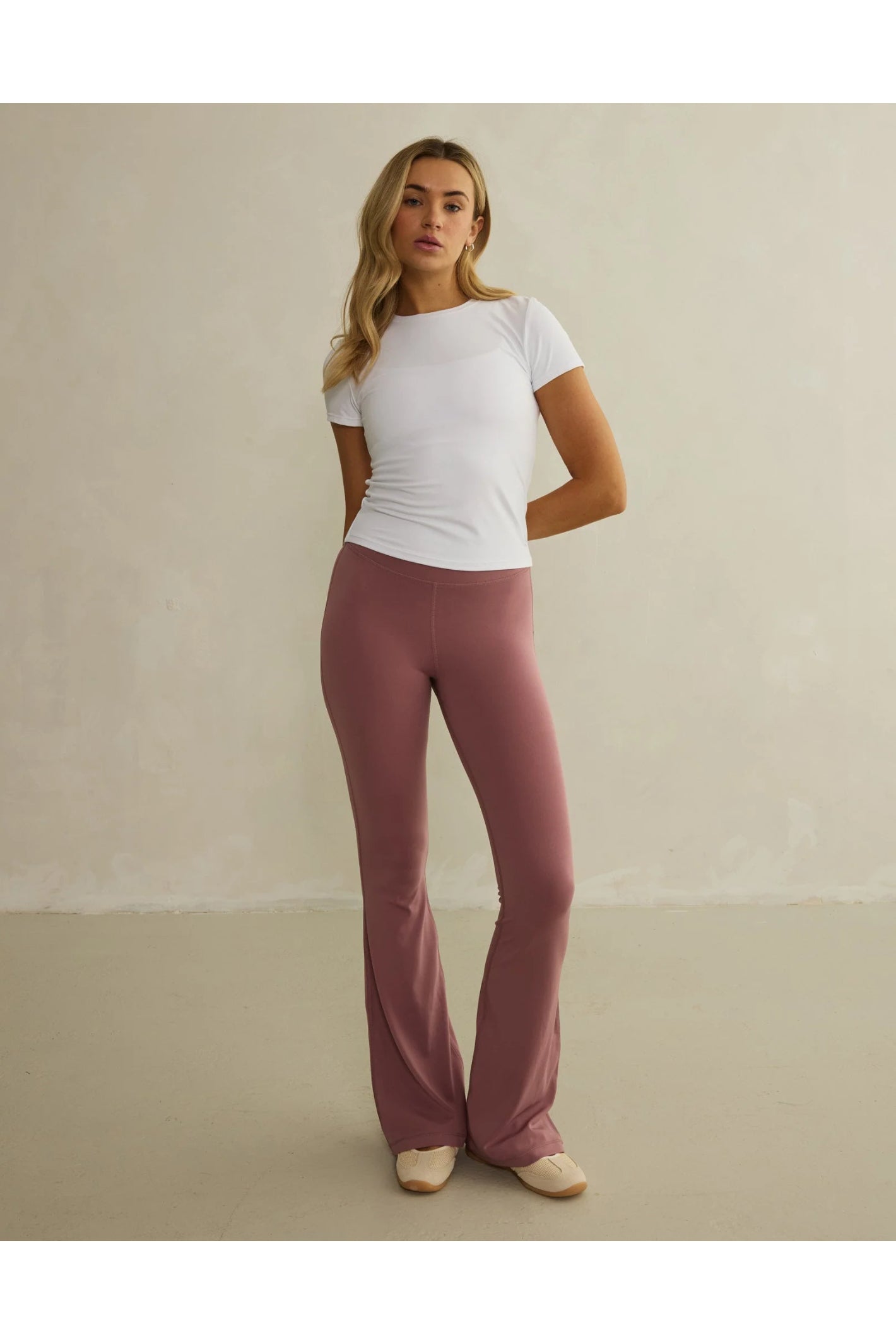 Model wearing Gym+Coffee Soft Motion Flares - Terra Rose flared leggings, shop Gym+Coffee at Dotique for stylish activewear essentials