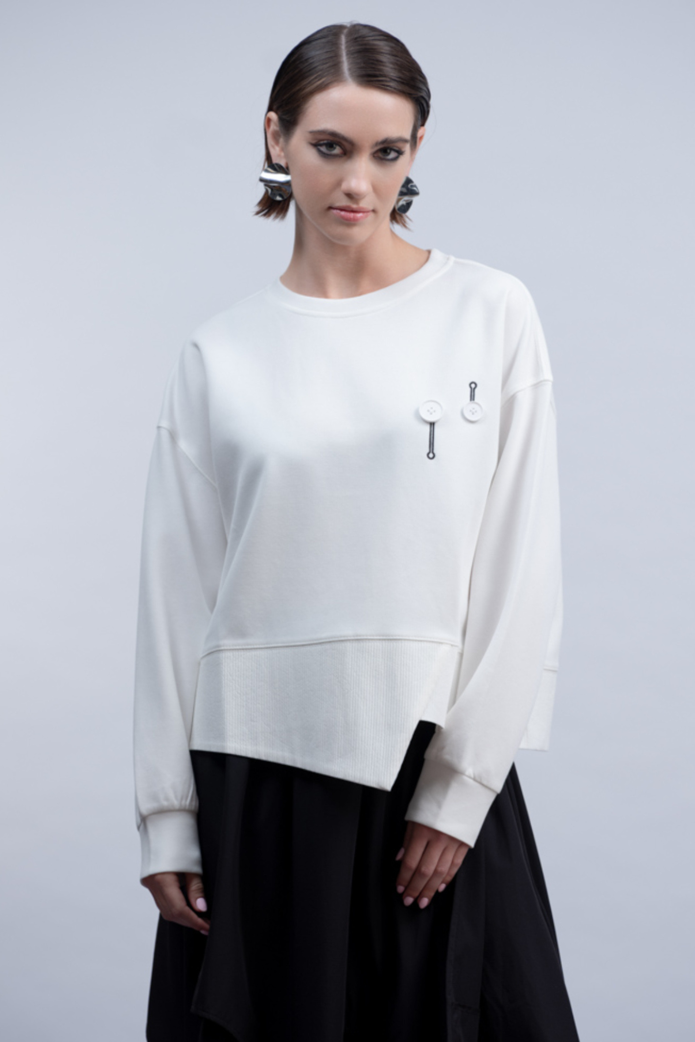 Shop the Haako H2046 white sweat top with quirky button and safety pin embroidered detail. An oversized crew neck top with asymmetric hem at Dotique.