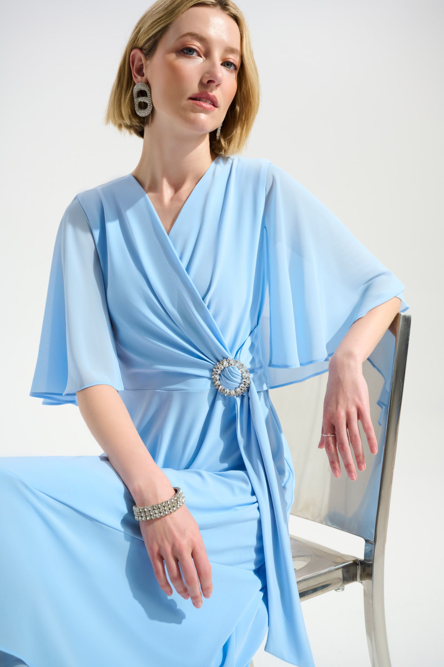 Joseph Ribkoff 261714 Sky Blue Signature Silky Knit Flowy Wrap Dress With Buckle Rhinestones Detail by joseph ribkoff shop at Dotique front seated view