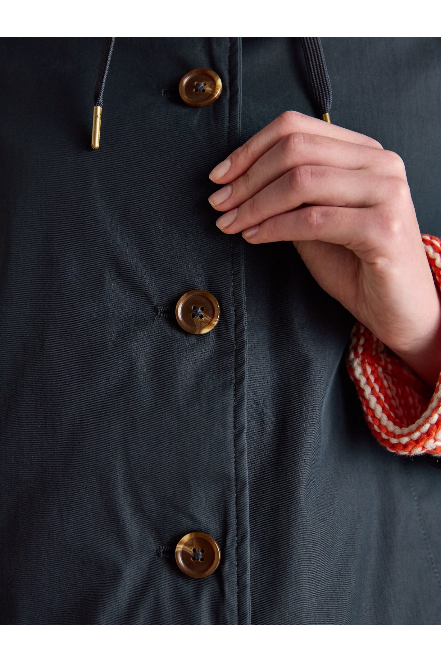 Close-up of buttons on Joules H23721 Rainmore Waterproof Coat – Navy held by a hand, shop Joules at Dotique.