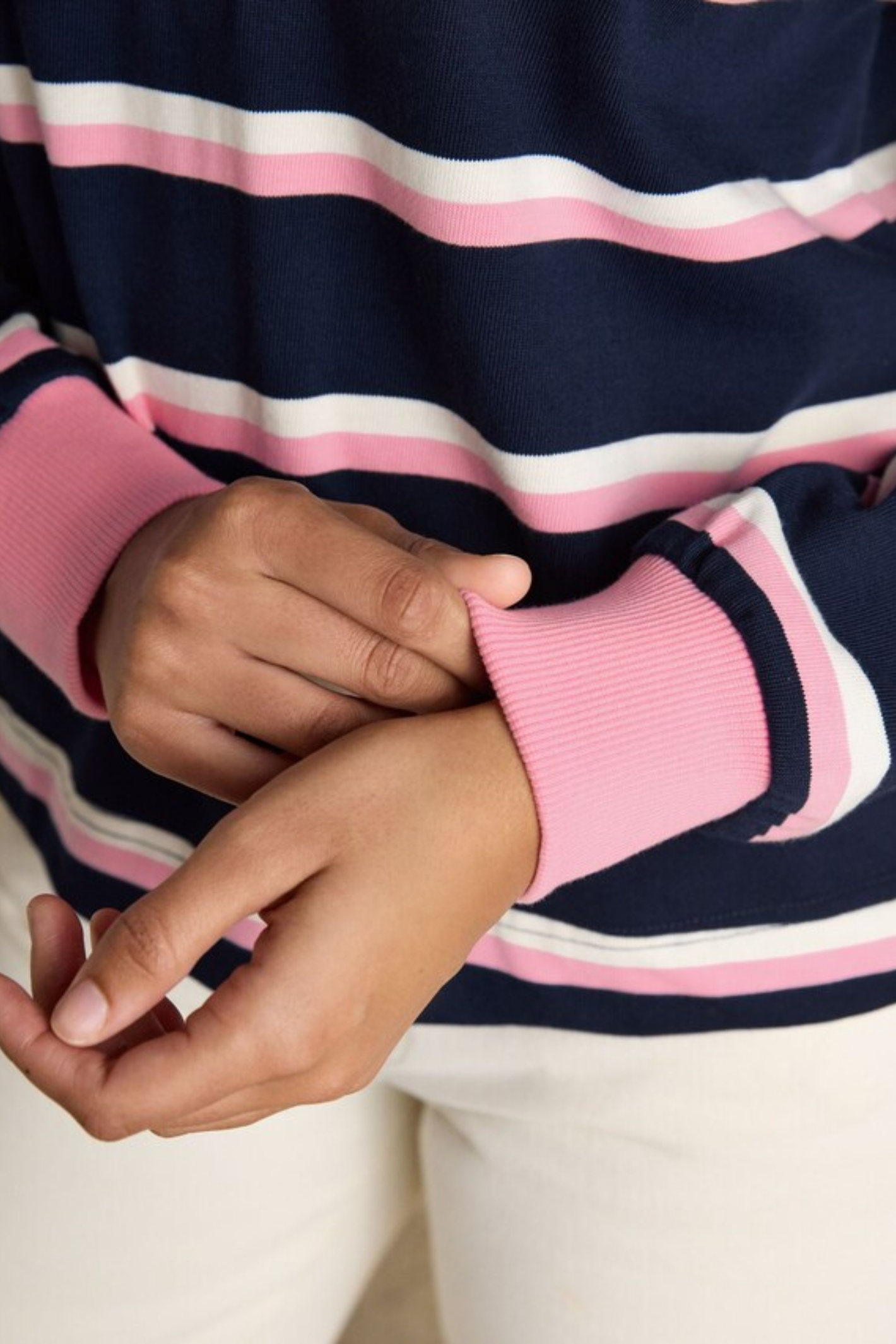 Close-up of hands wearing Joules W30854 Lara Rugby Shirt – Navy / Pink Stripe by Joules, shop at Dotique.